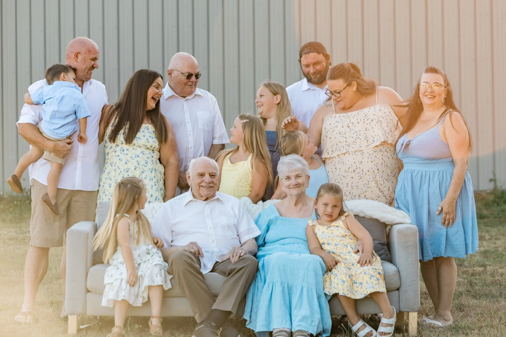 Grandparents, parents and cousins laughing together on and around the couch in the field
