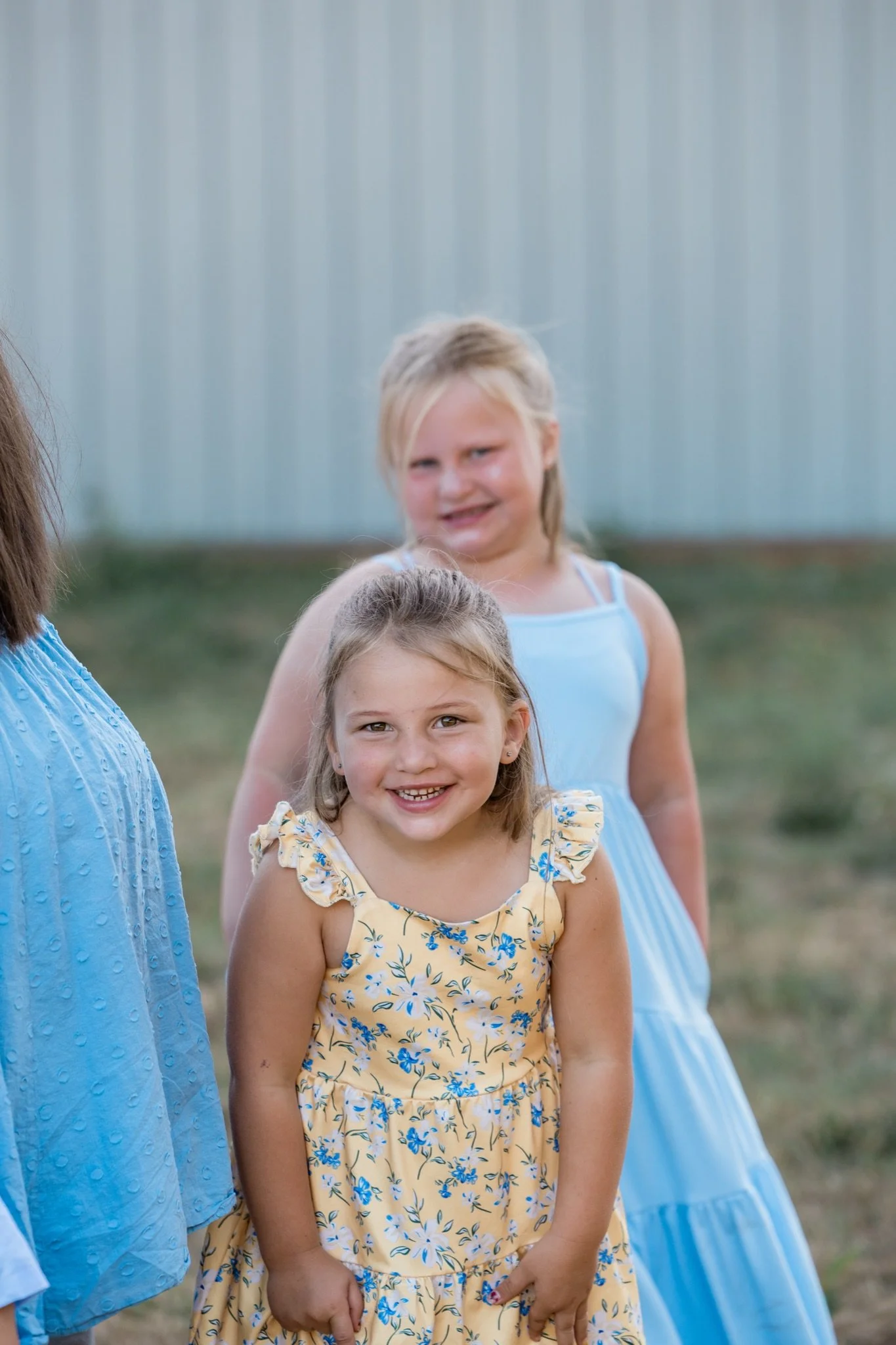 A little girl in a yellow floral dress with her mom in blue beside her