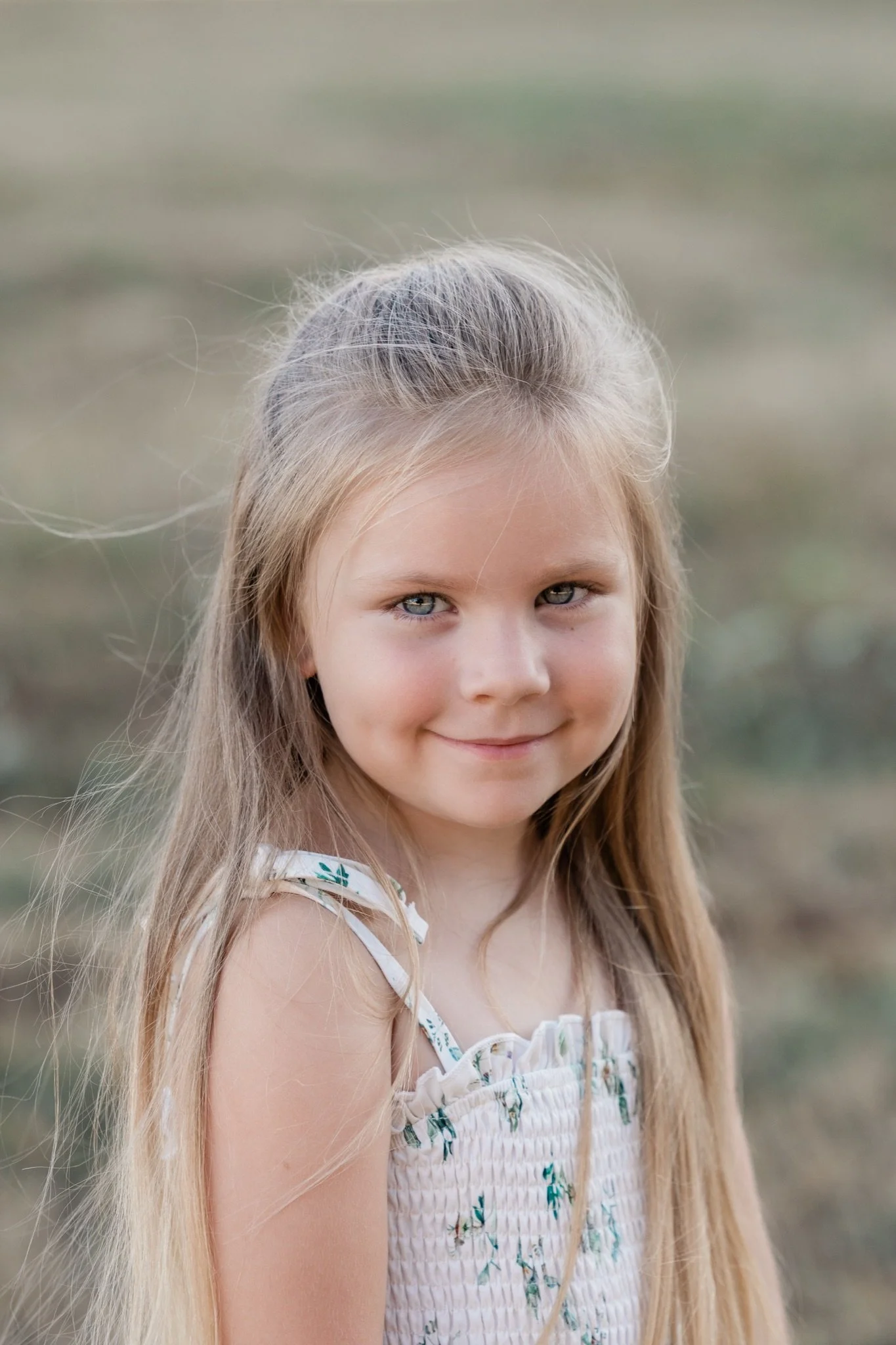 A little girl with long hair smiling in the evening light