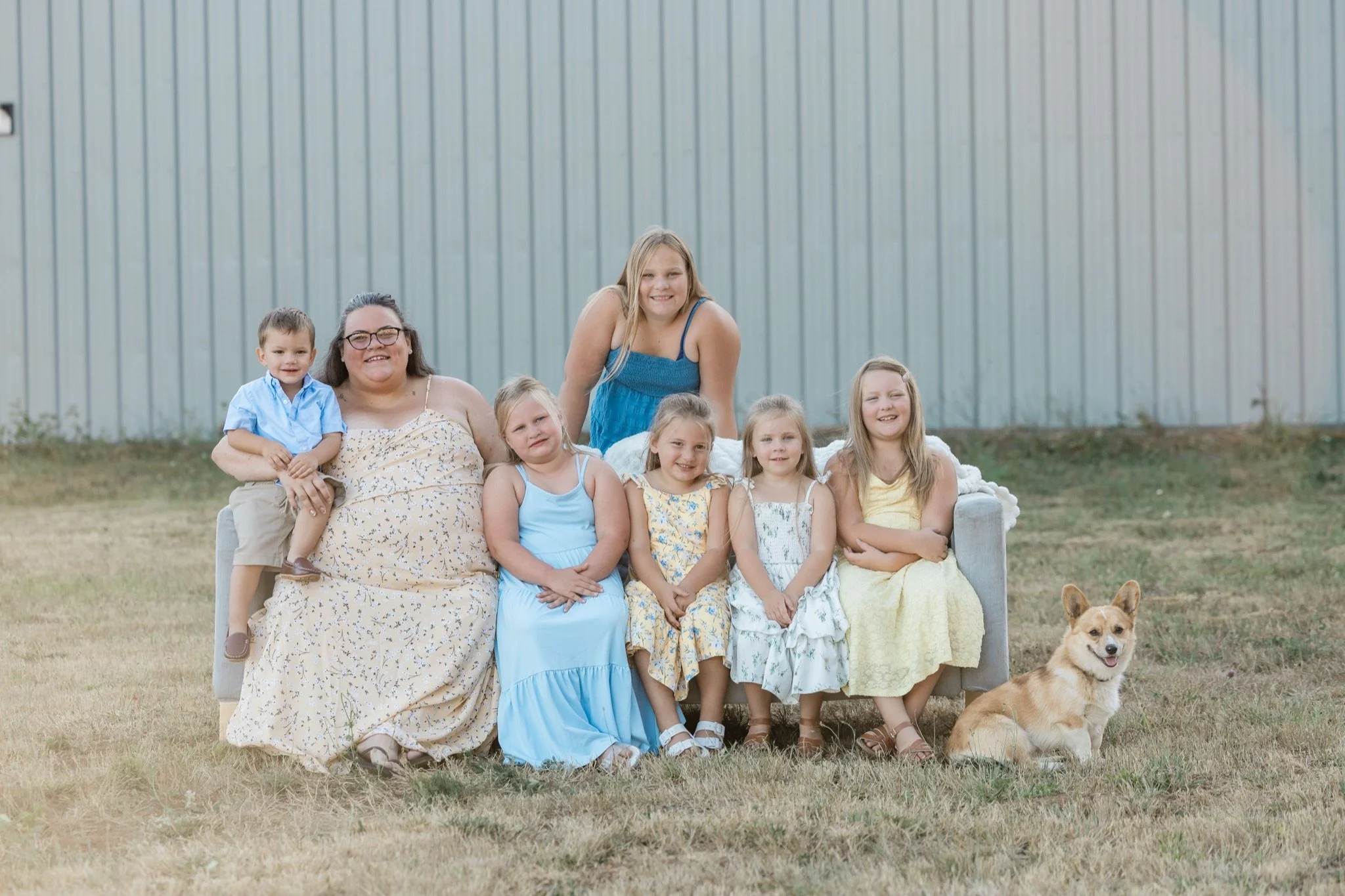 Parents, kids and the corgi on the couch in the summer field