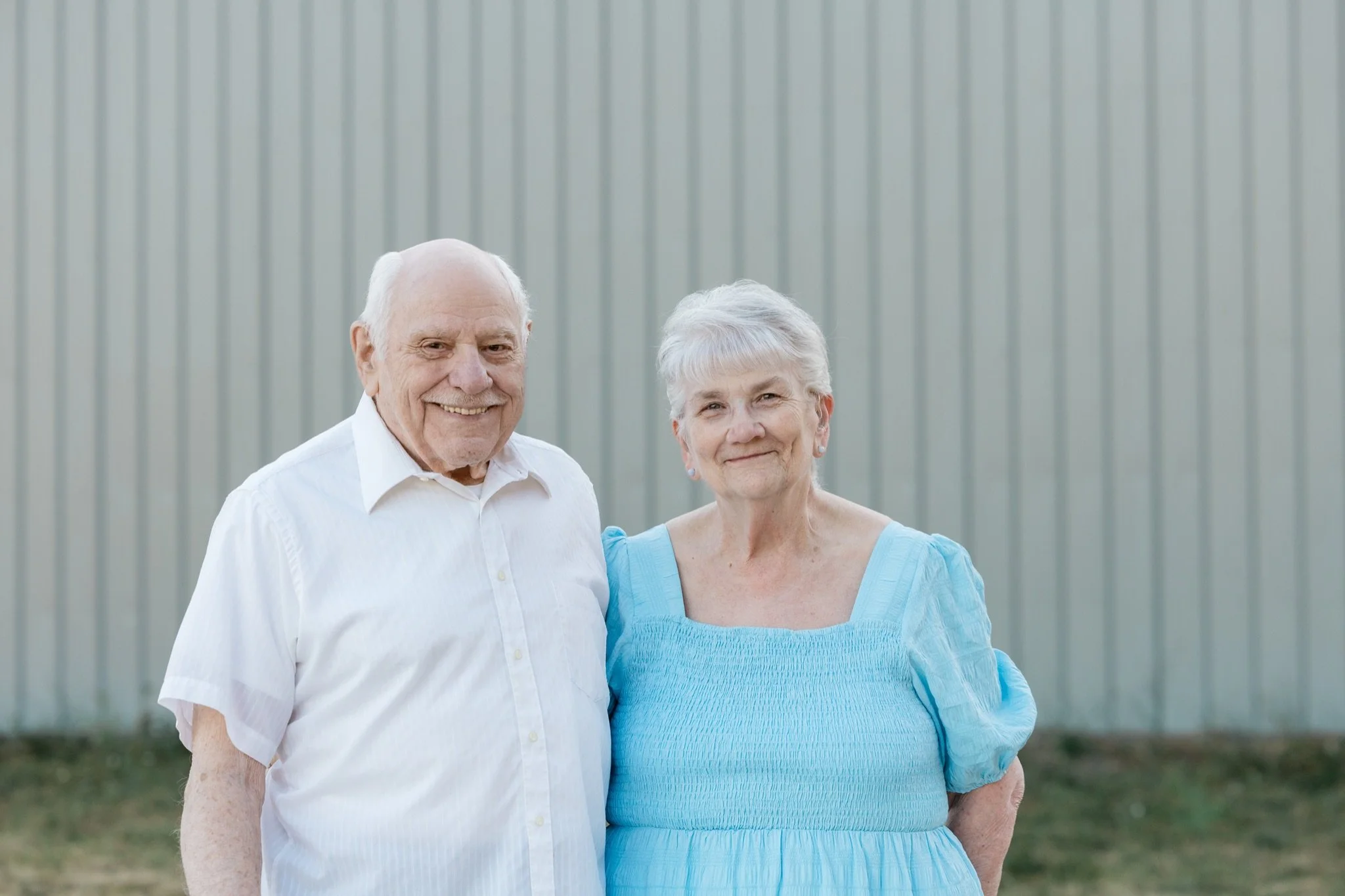 Grandpa in white and grandma in blue standing together in the evening light