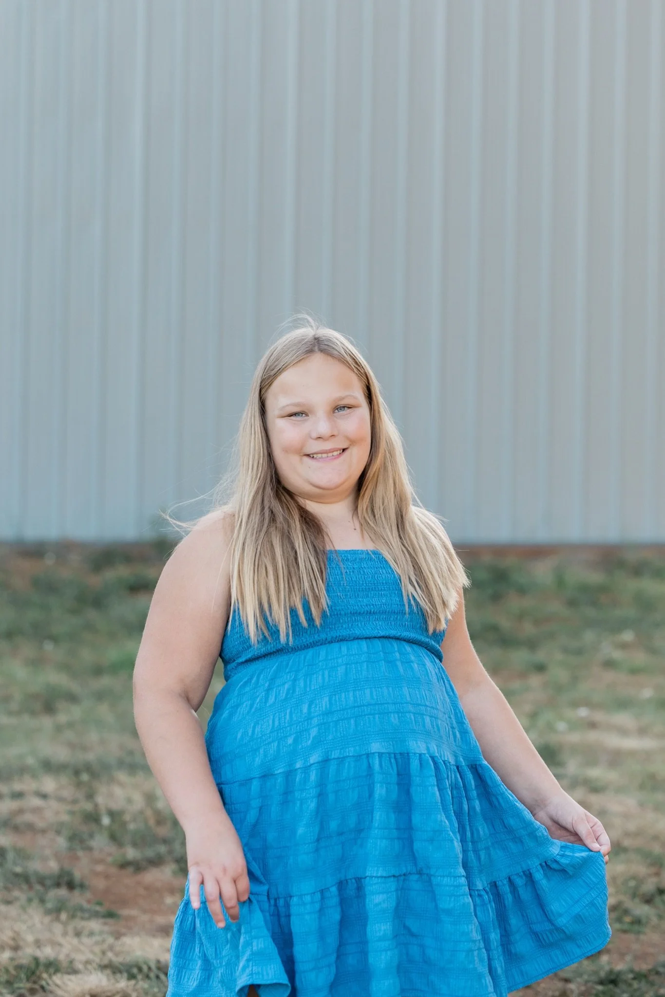 A girl in a bright blue dress standing in the summer grass