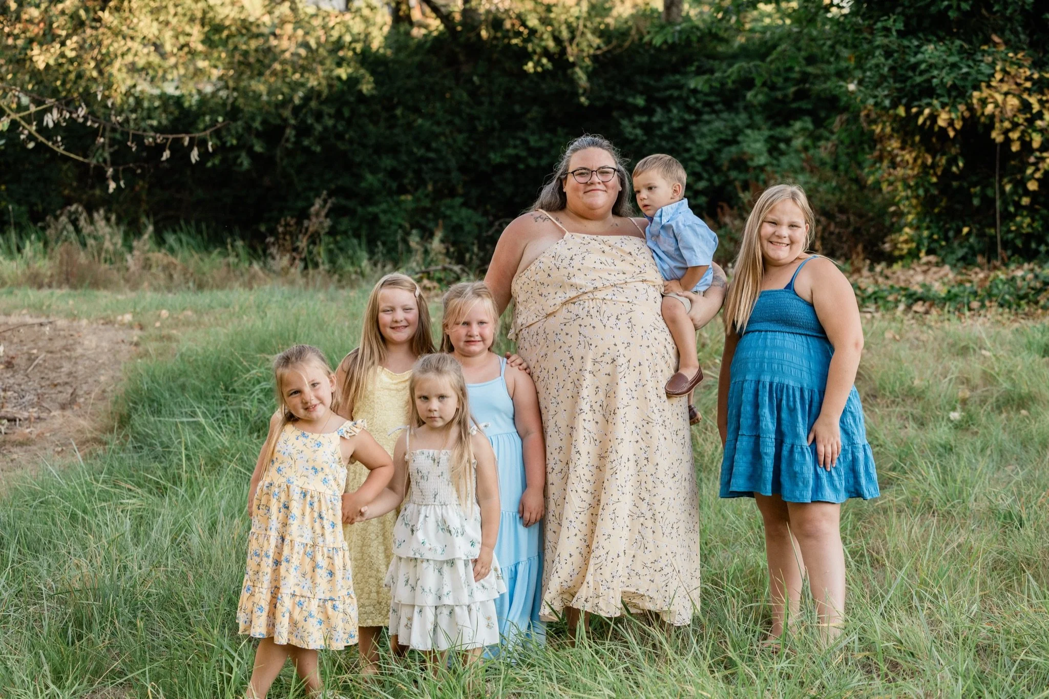 Mom and her daughters in yellow and blue on the lane by the trees