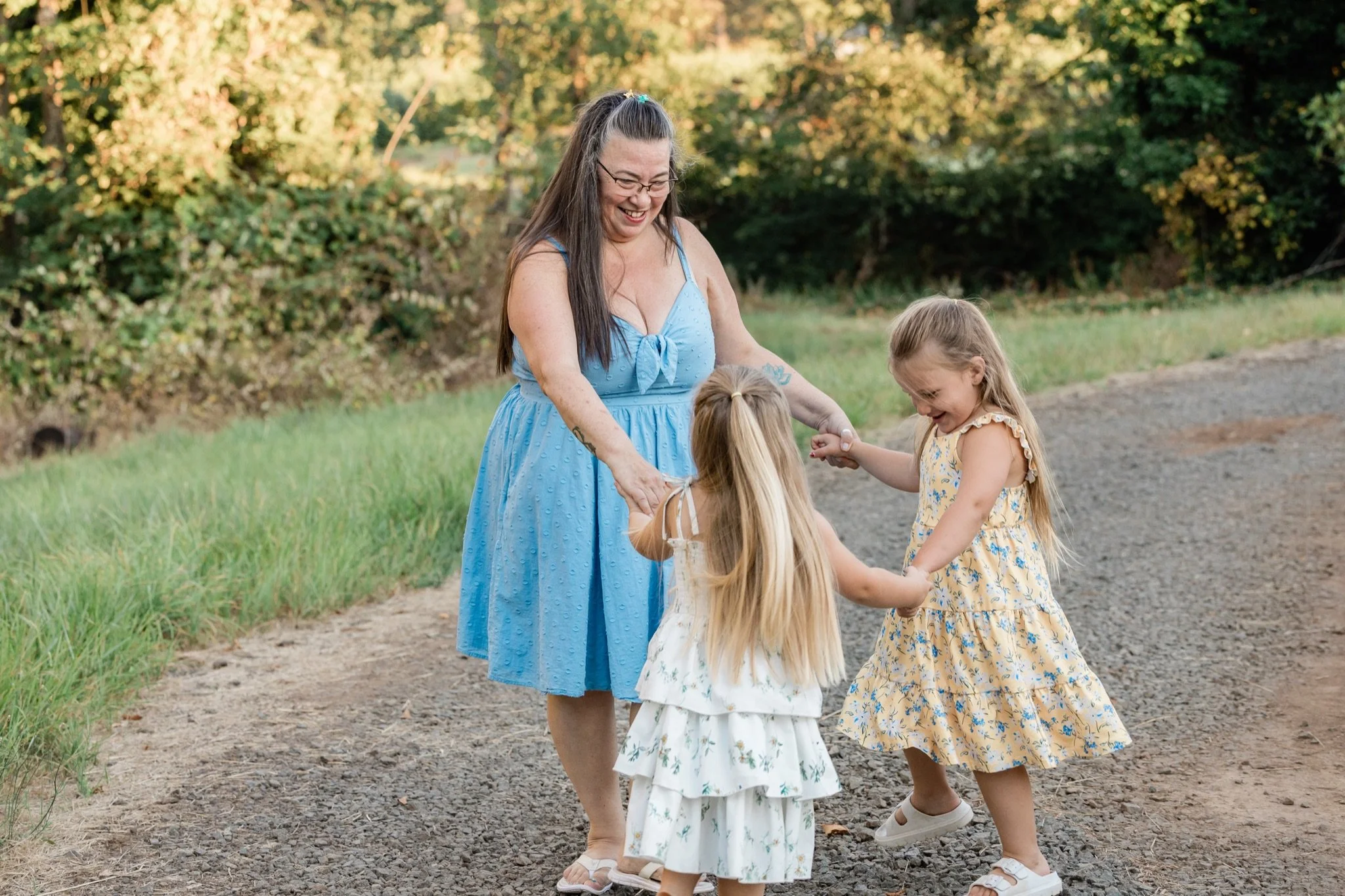 Mom holding hands with her two little girls on the country lane