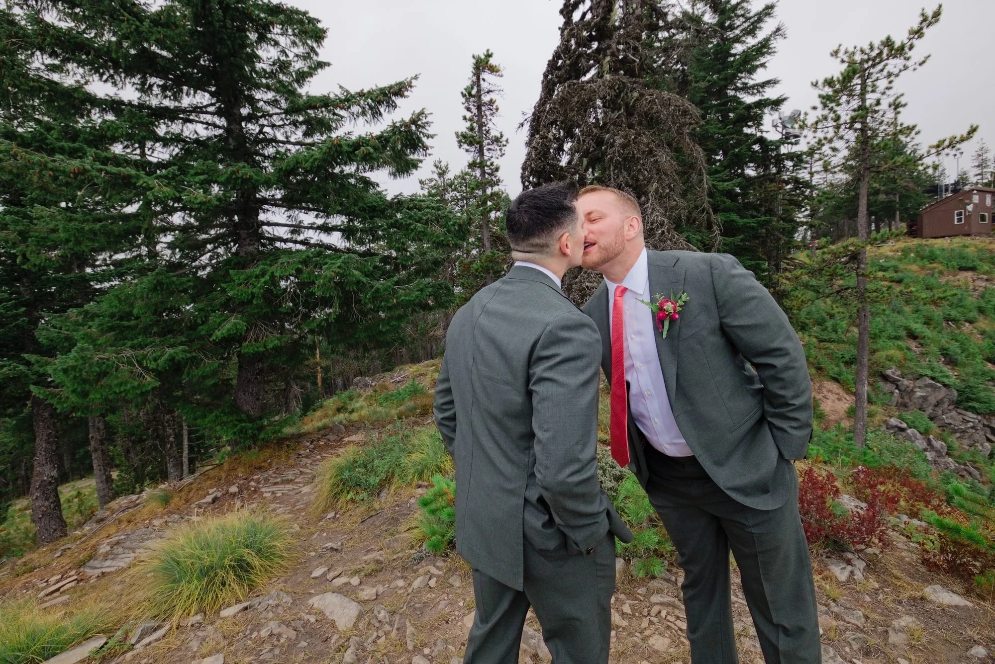 Rick and Mason kissing on the rocky overlook at Mt. Hood Skibowl in their green suits