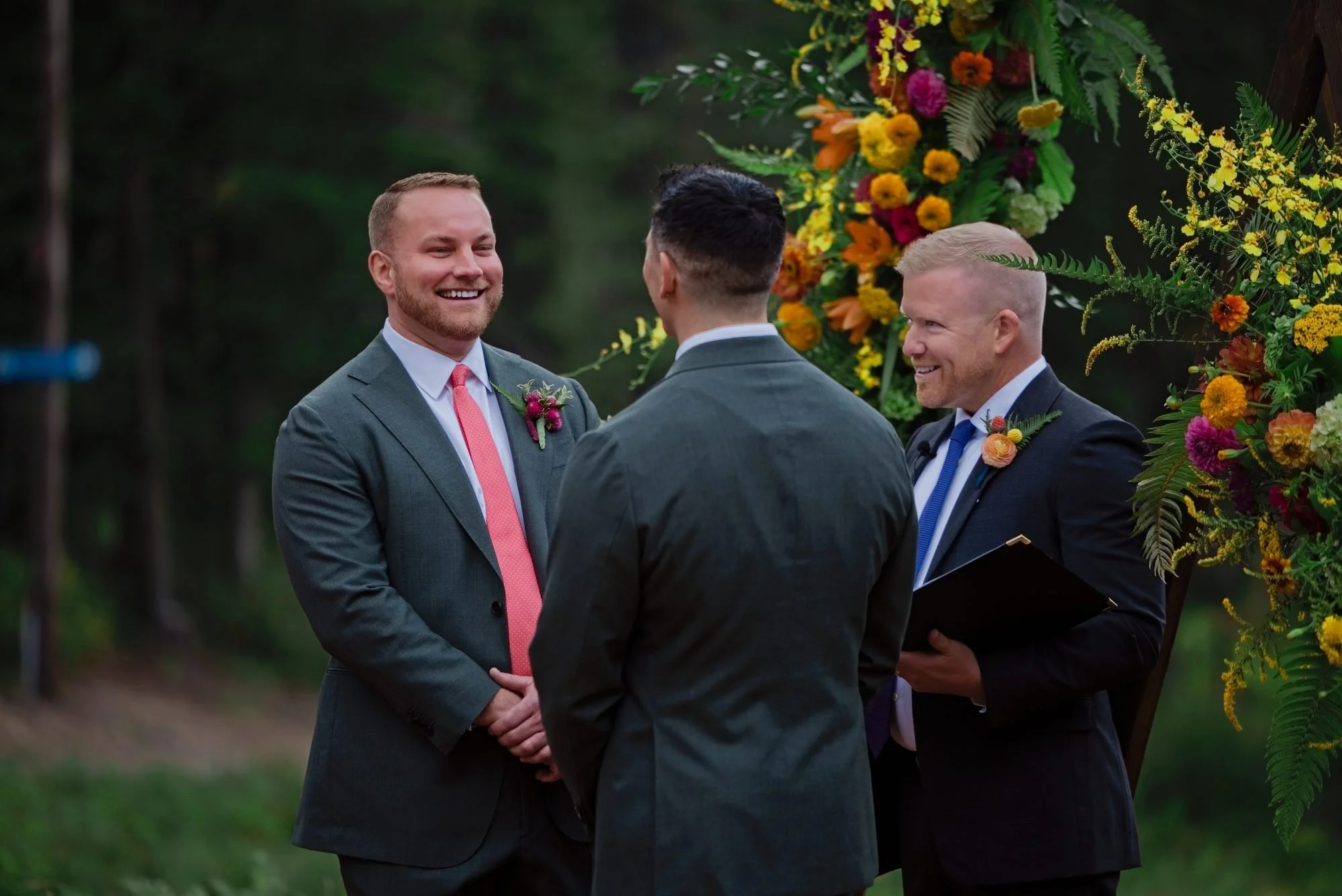 Rick and Mason at the altar with the officiant and the flower covered arch