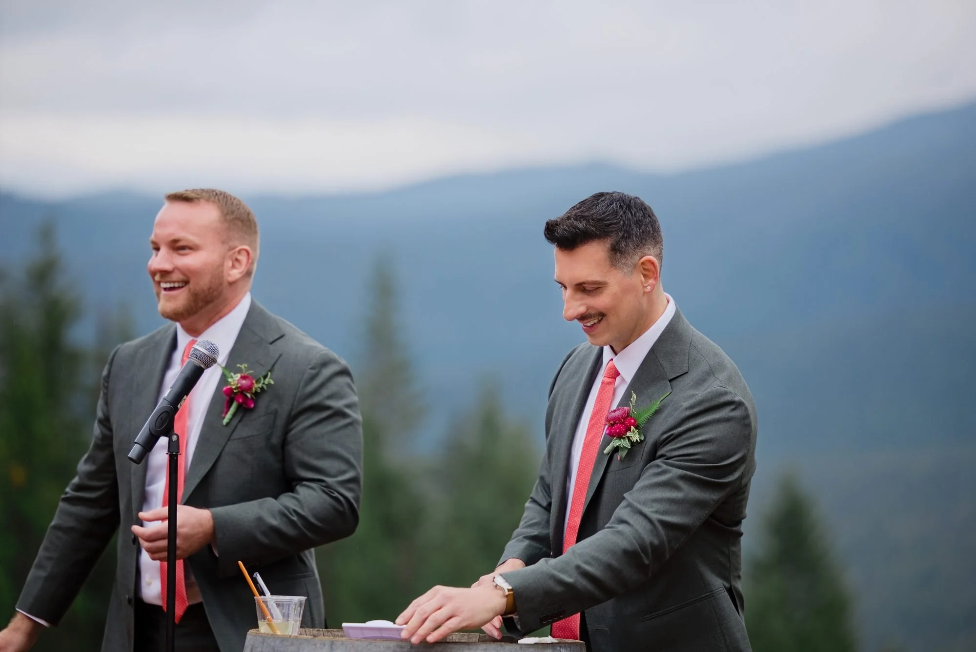 The grooms laughing during the ceremony with the Mt. Hood foothills behind them
