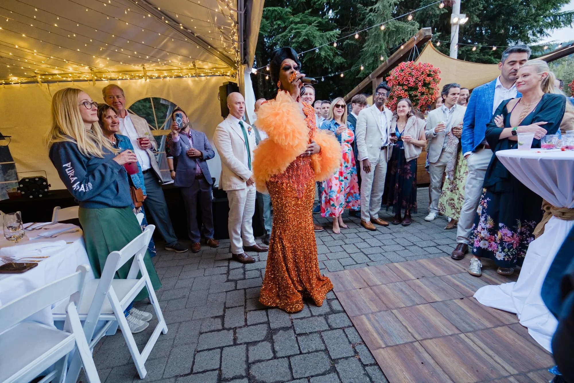 Guests under the tent at the reception at the base of Mt. Hood Skibowl with a performer in orange