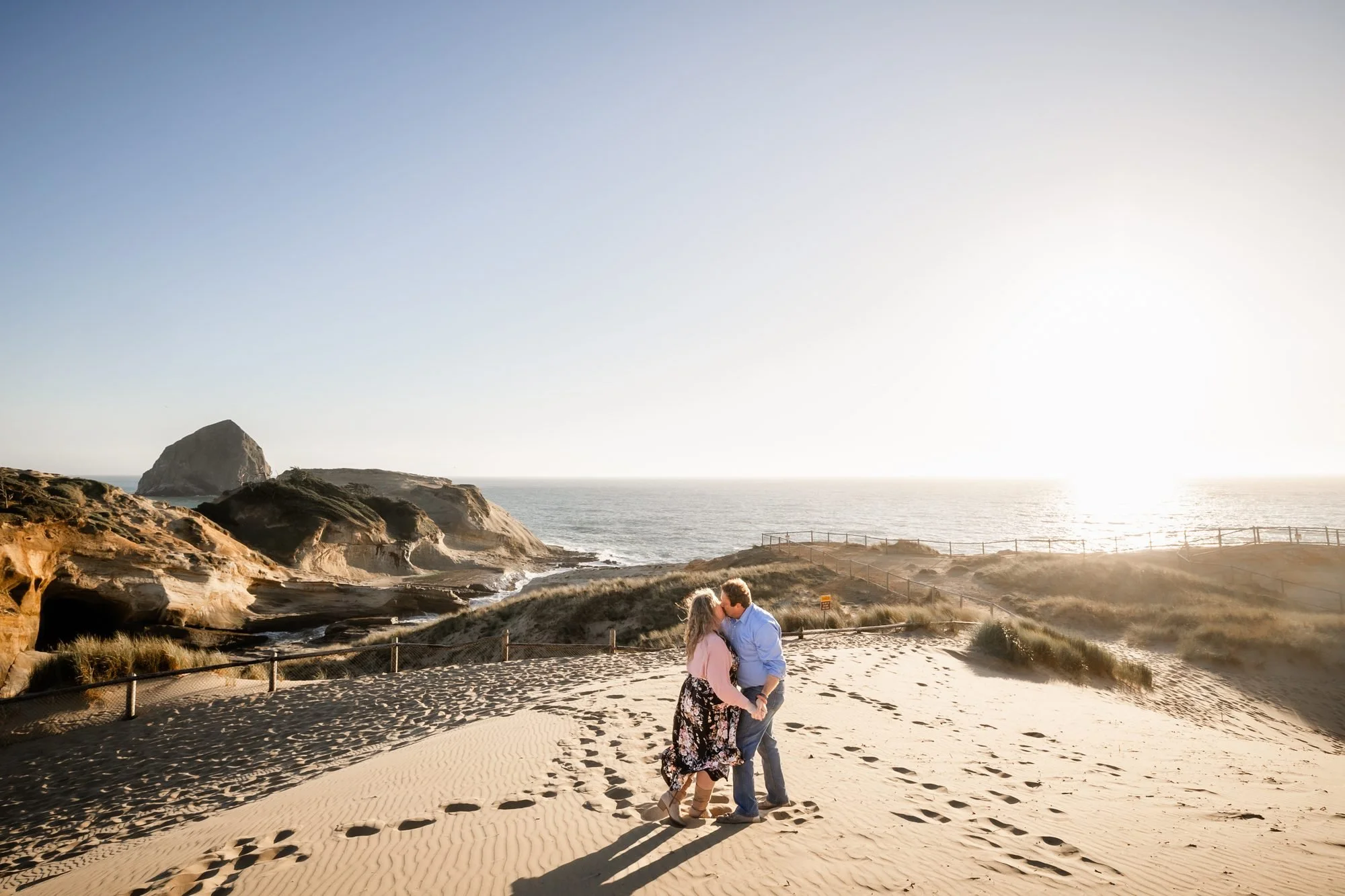 Tori and Jamie walking across the sand toward Haystack Rock at Cape Kiwanda at sunset
