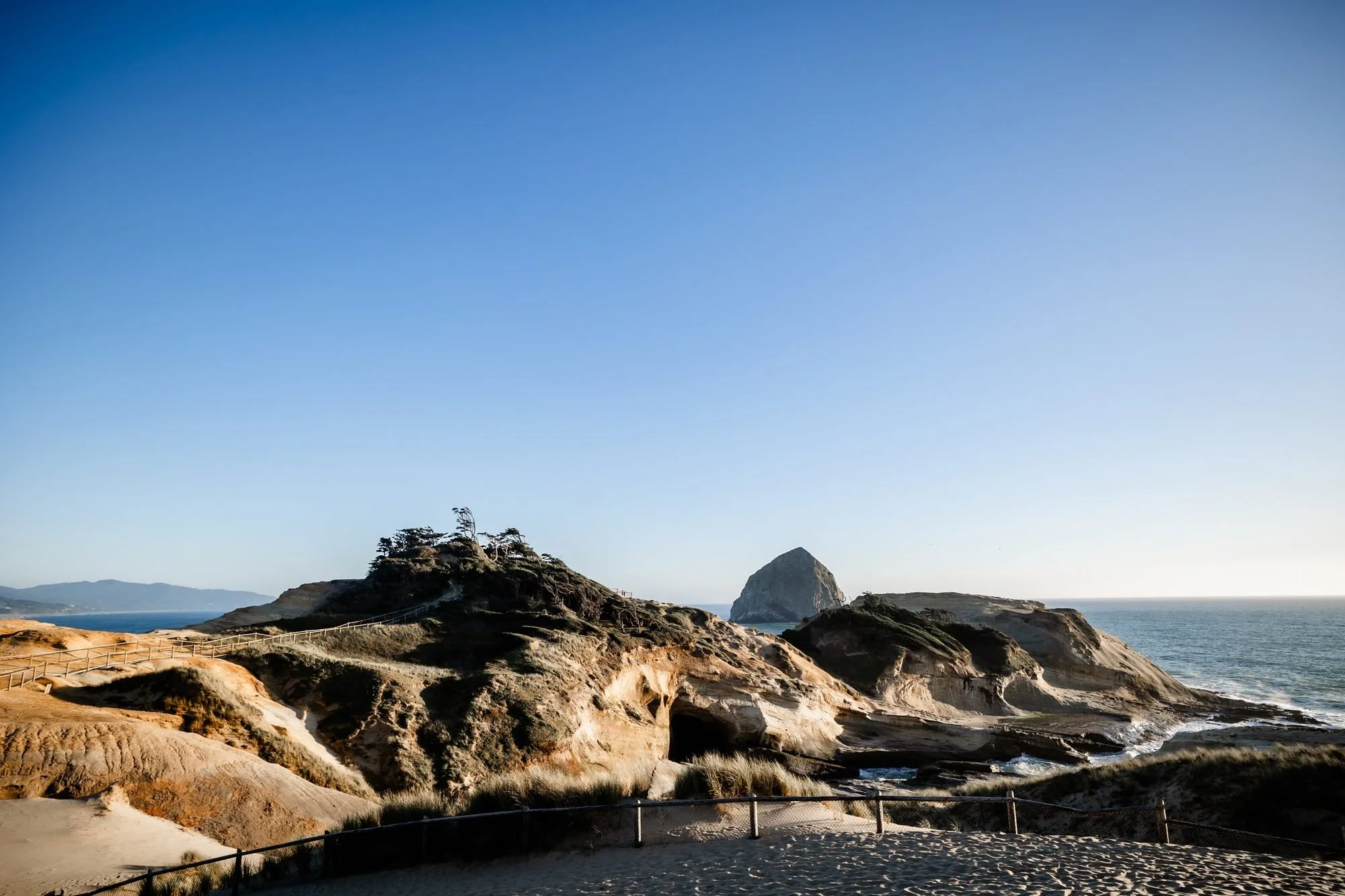 The sandstone cliffs and Haystack Rock at Cape Kiwanda under a clear blue sky