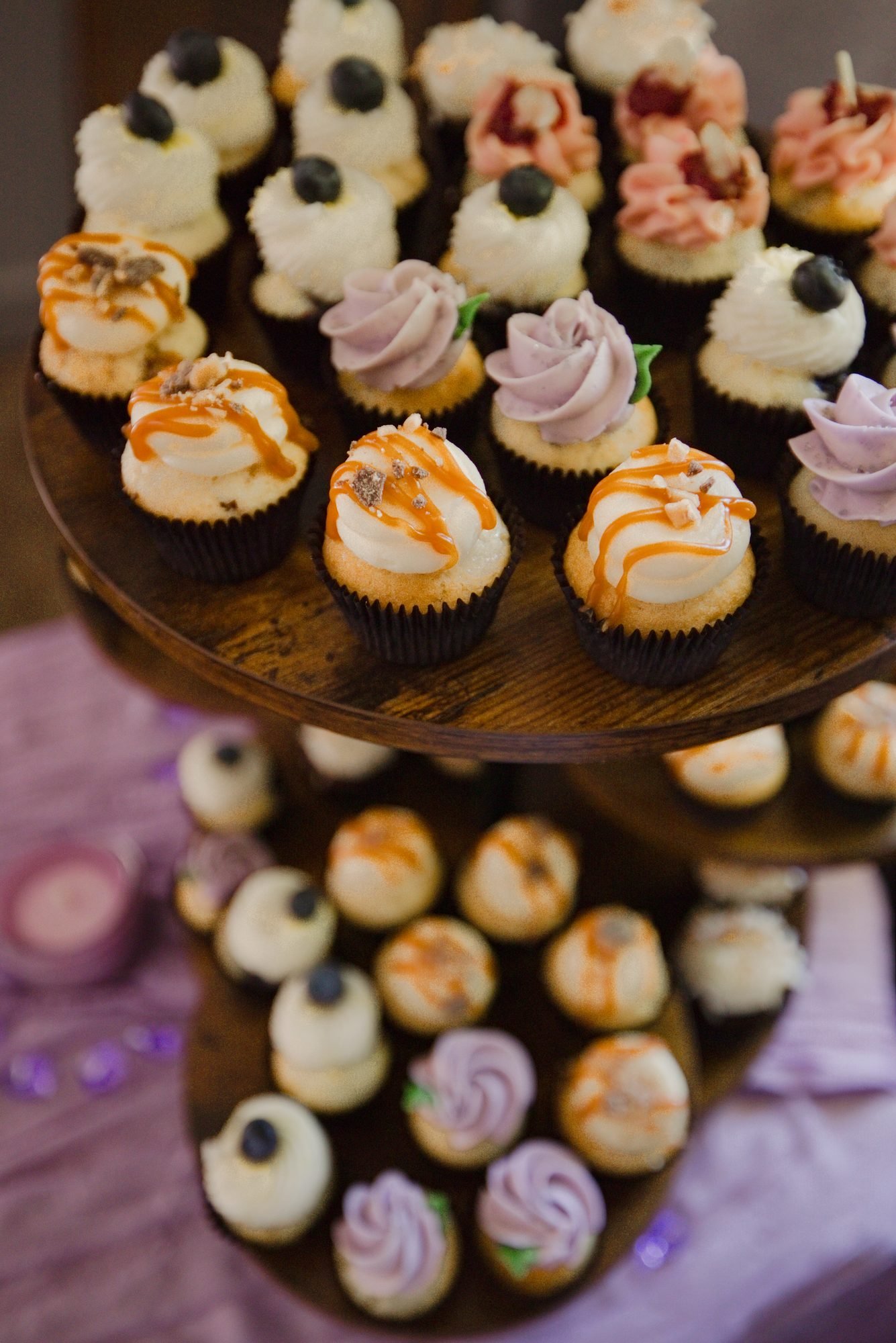 Mini cupcakes with lavender and caramel frosting on a wooden stand at the reception