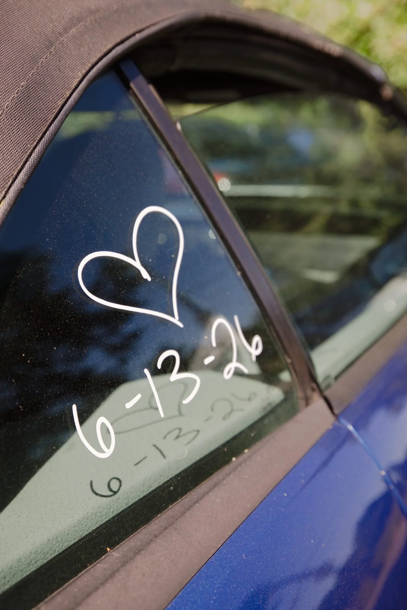 A heart and the wedding date 6 13 26 written on the window of the getaway car