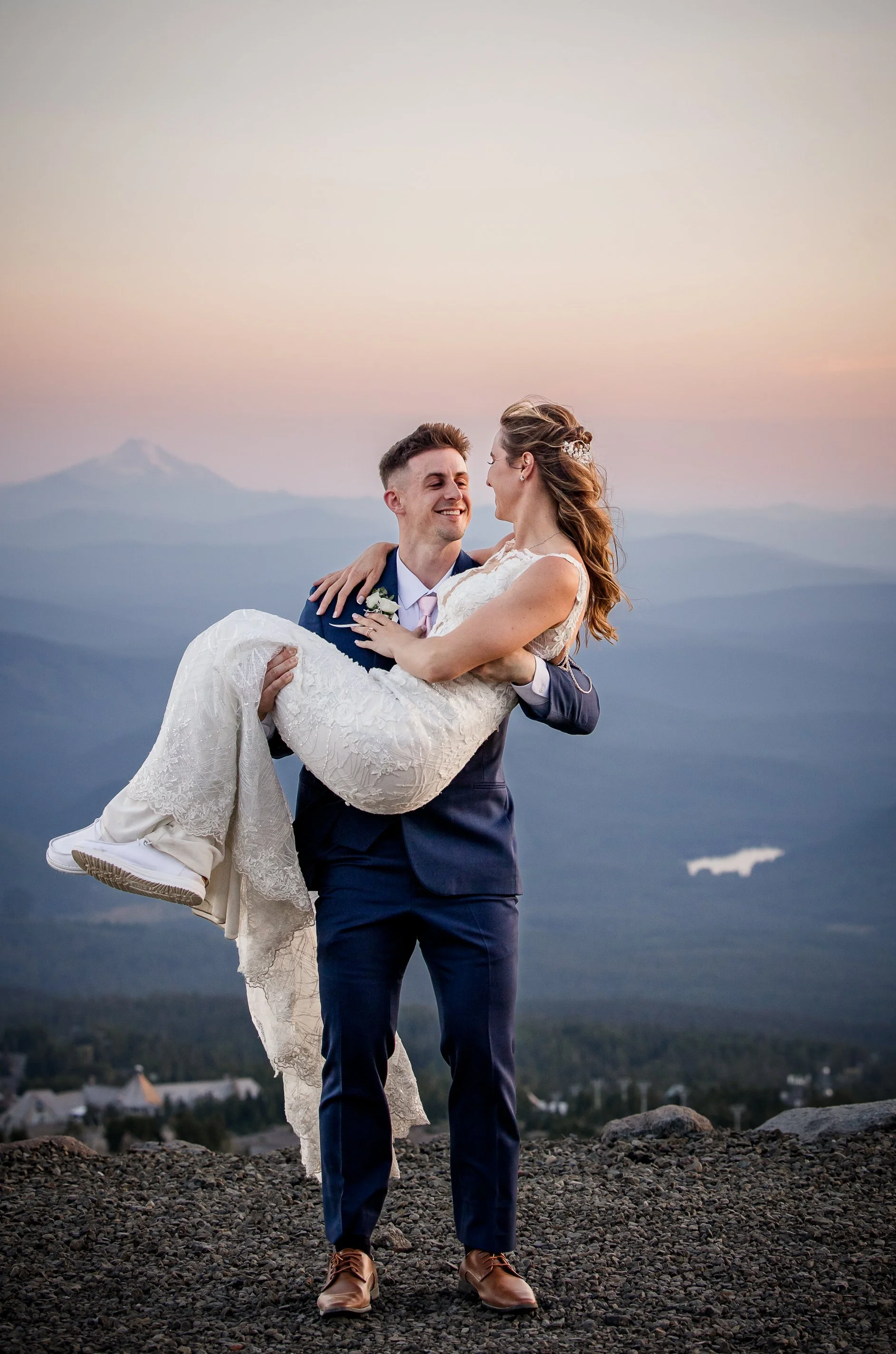 Groom carrying his bride at dusk high on Mt. Hood after their Timberline Lodge wedding ceremony