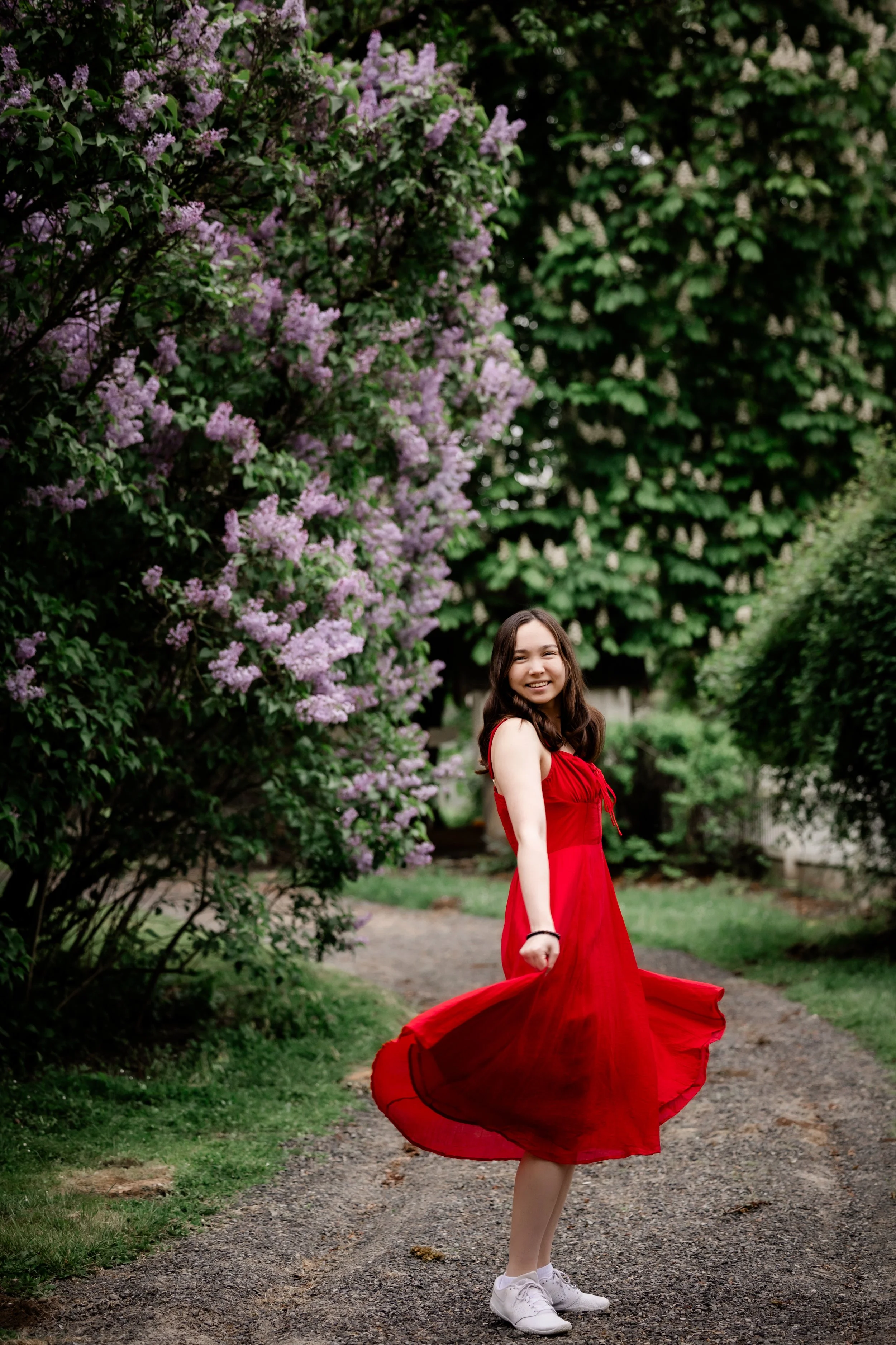 Reynolds High School senior in red dress twirling beneath blooming lilacs in Sandy, Oregon