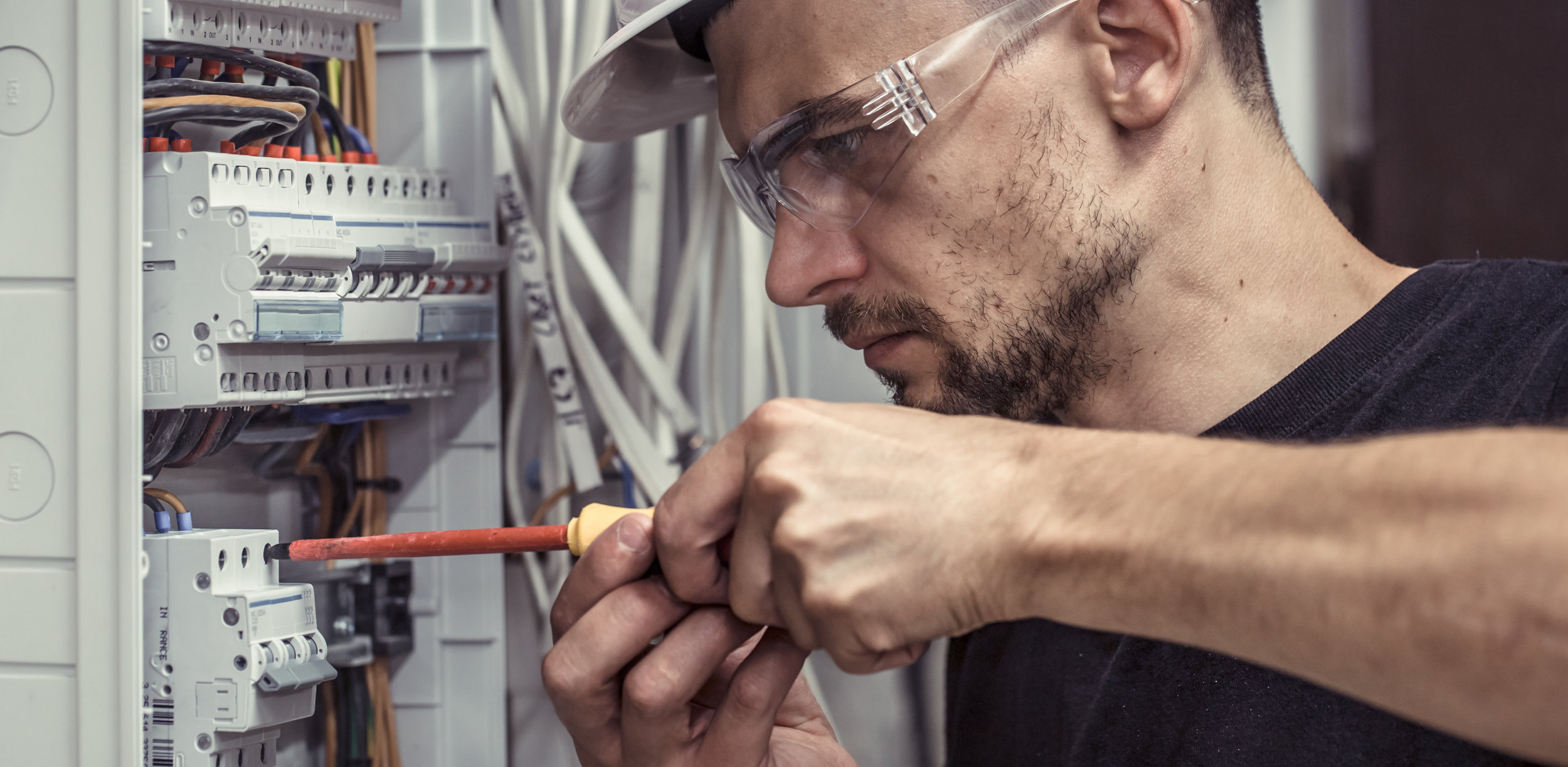 a male electrician works in a switchboard with an electrical connecting cable.jpeg