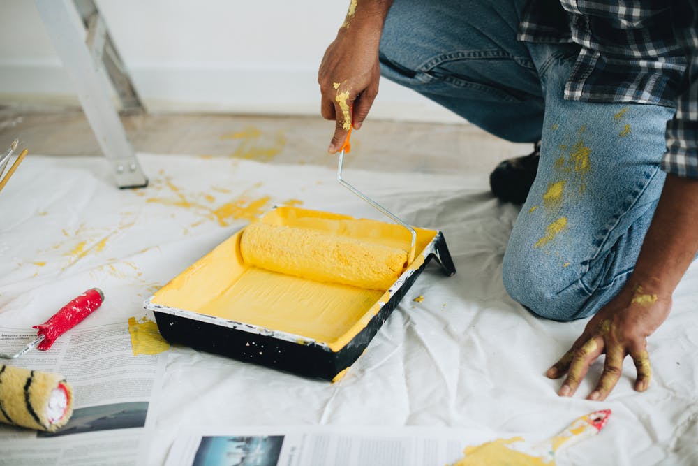 yellow paint in tray with person holding roller