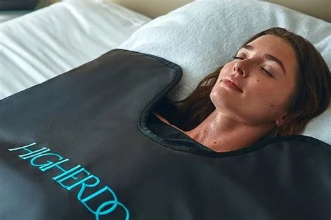 Woman lying on a bed with eyes closed, covered by a hyperbaric oxygen therapy chamber.