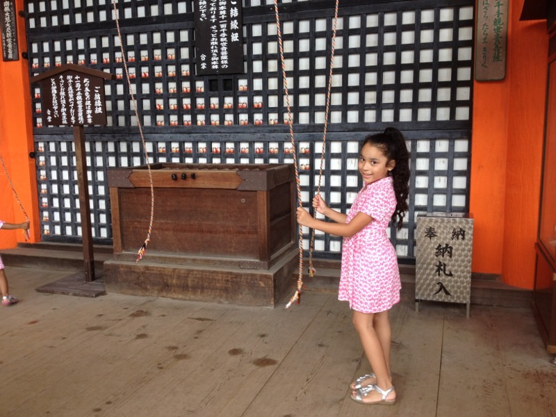 Mia pulls on the ropes to ring the temple bells