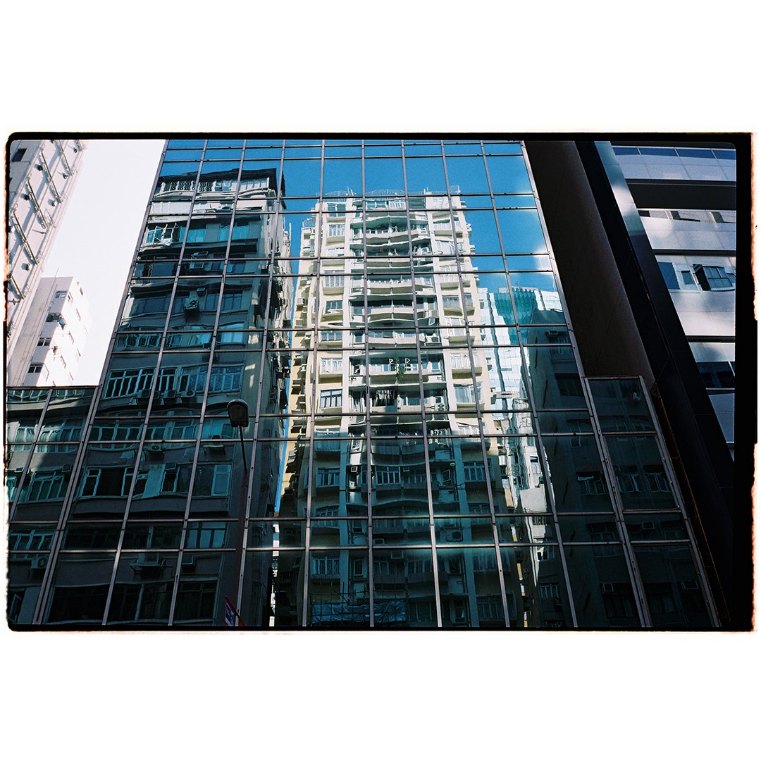 Reflection of a residential building in a glass window on a modern office building.