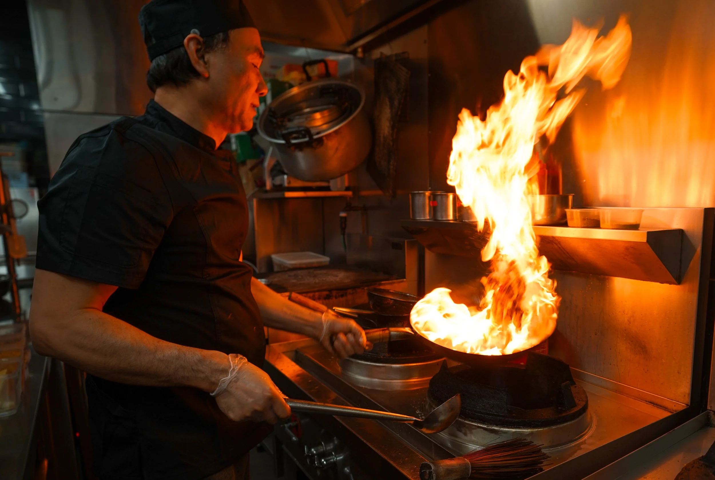 Chef cooking with flame in commercial kitchen
