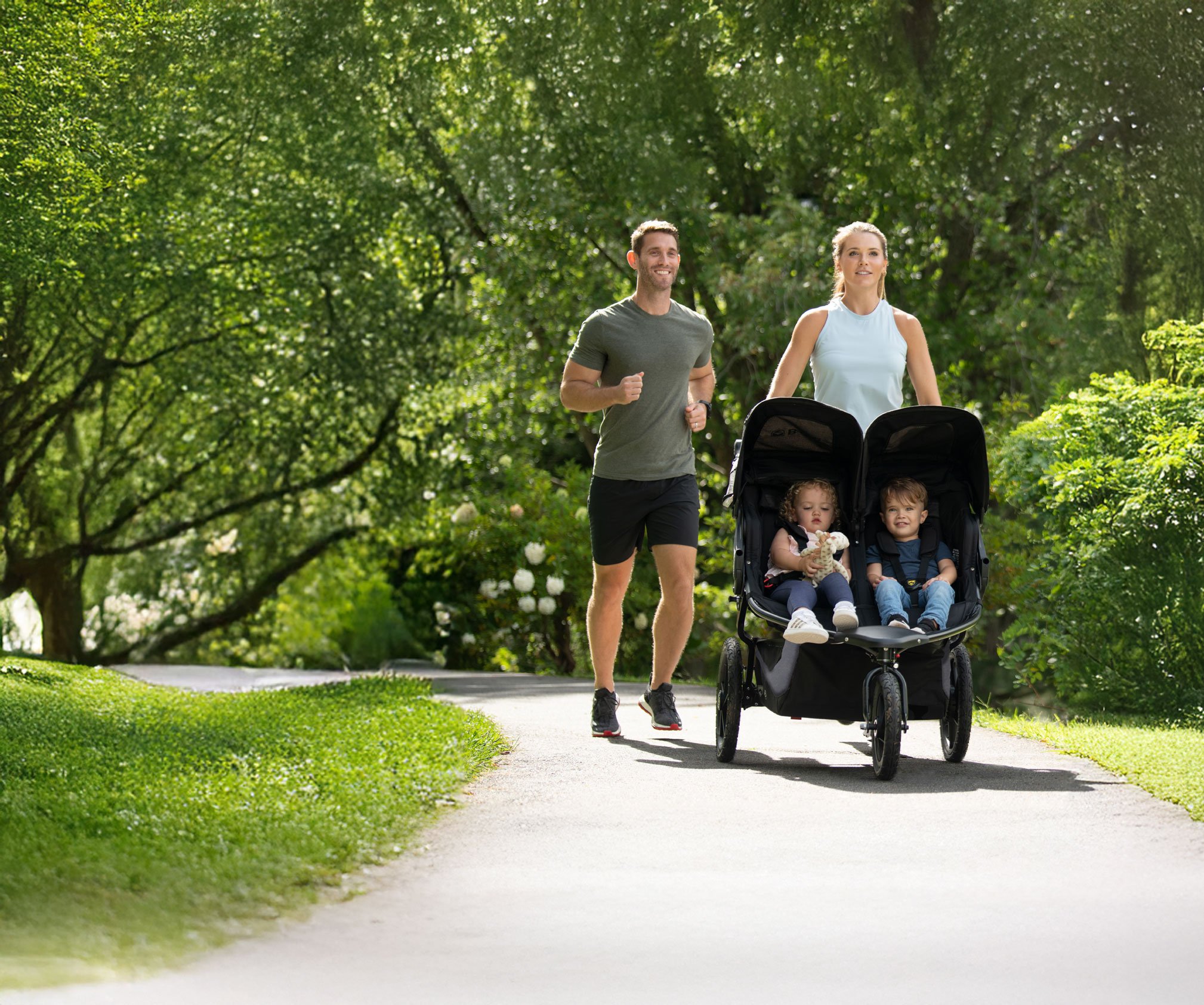 Family jogging through a park with a Duallie Stroller