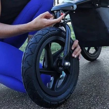 mom flipping a switch on the front wheel of her jogging stroller