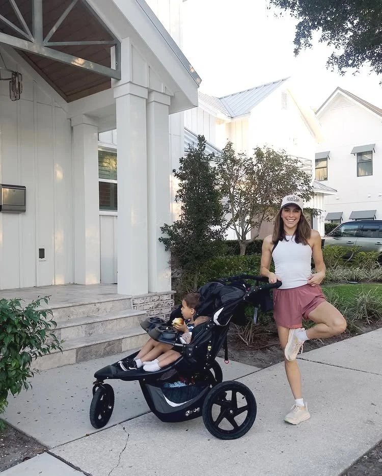 mom doing a yoga pose with their child in a jogging stroller