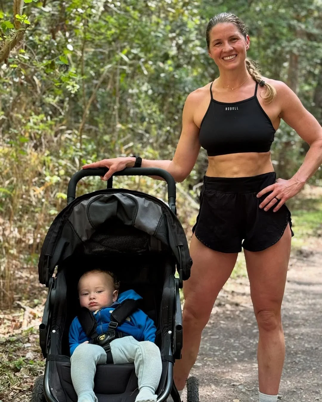 A mom with her baby in a stroller while walking through a park