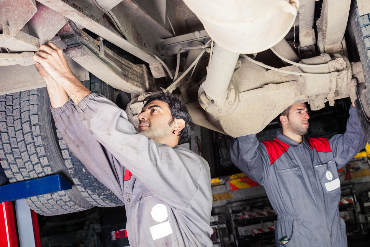 Mechanics inspecting a truck for maintenance.