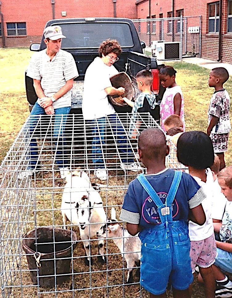   Woody loves animals and children. Here she is sharing her goats at the local school.&nbsp;  