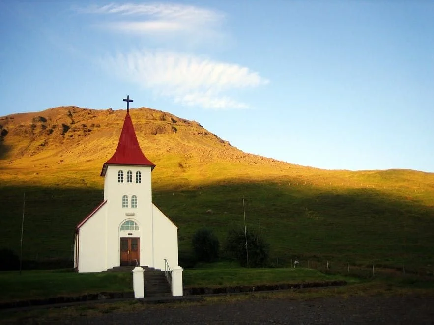 white-church-red-steeple-golden-hillside-iceland-2026.jpeg