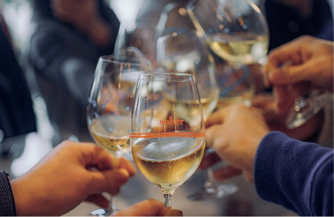 People toasting with glasses of white wine.