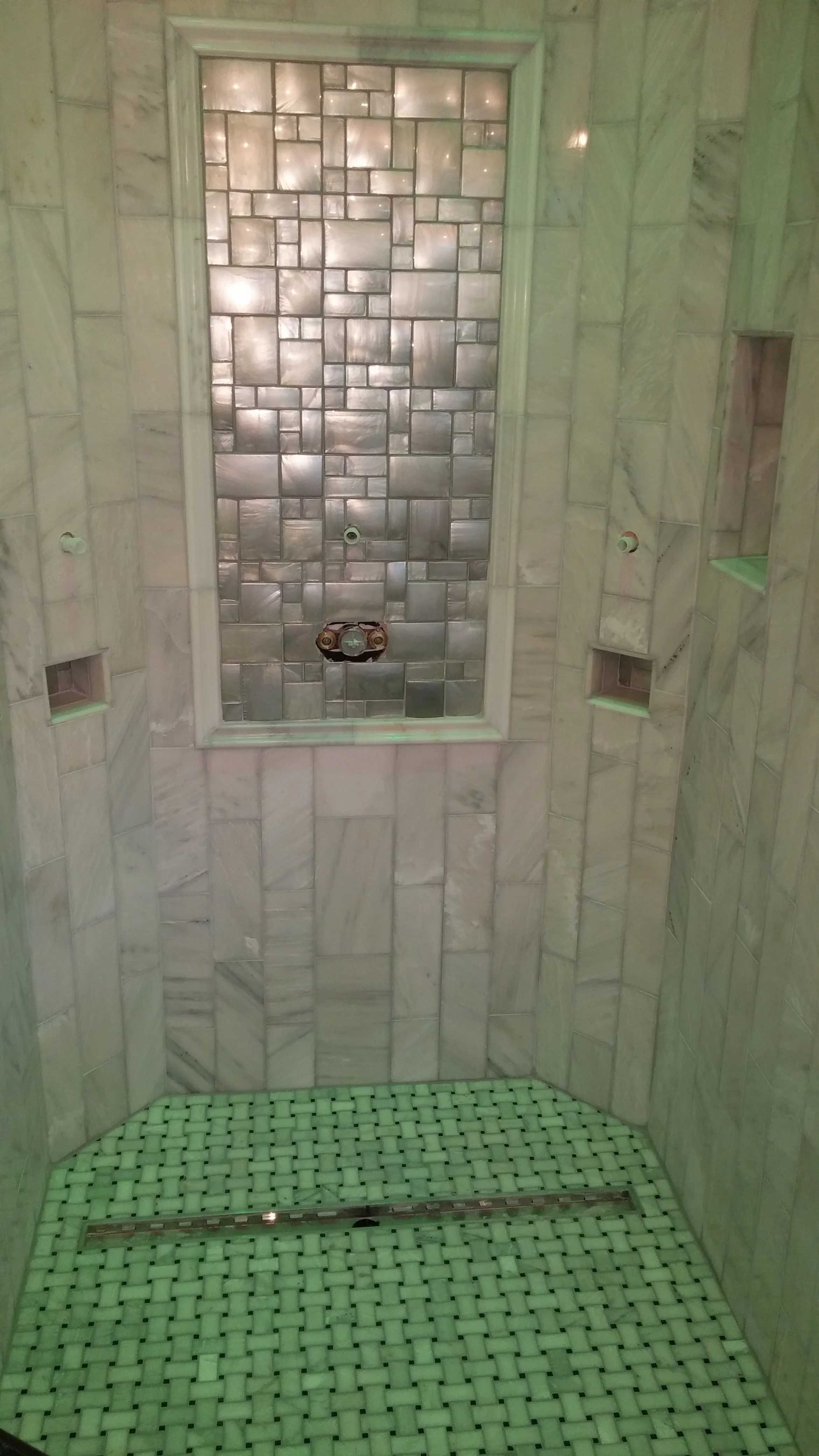Marble shower with lineal drain and inlay with niches in Louisville CO.