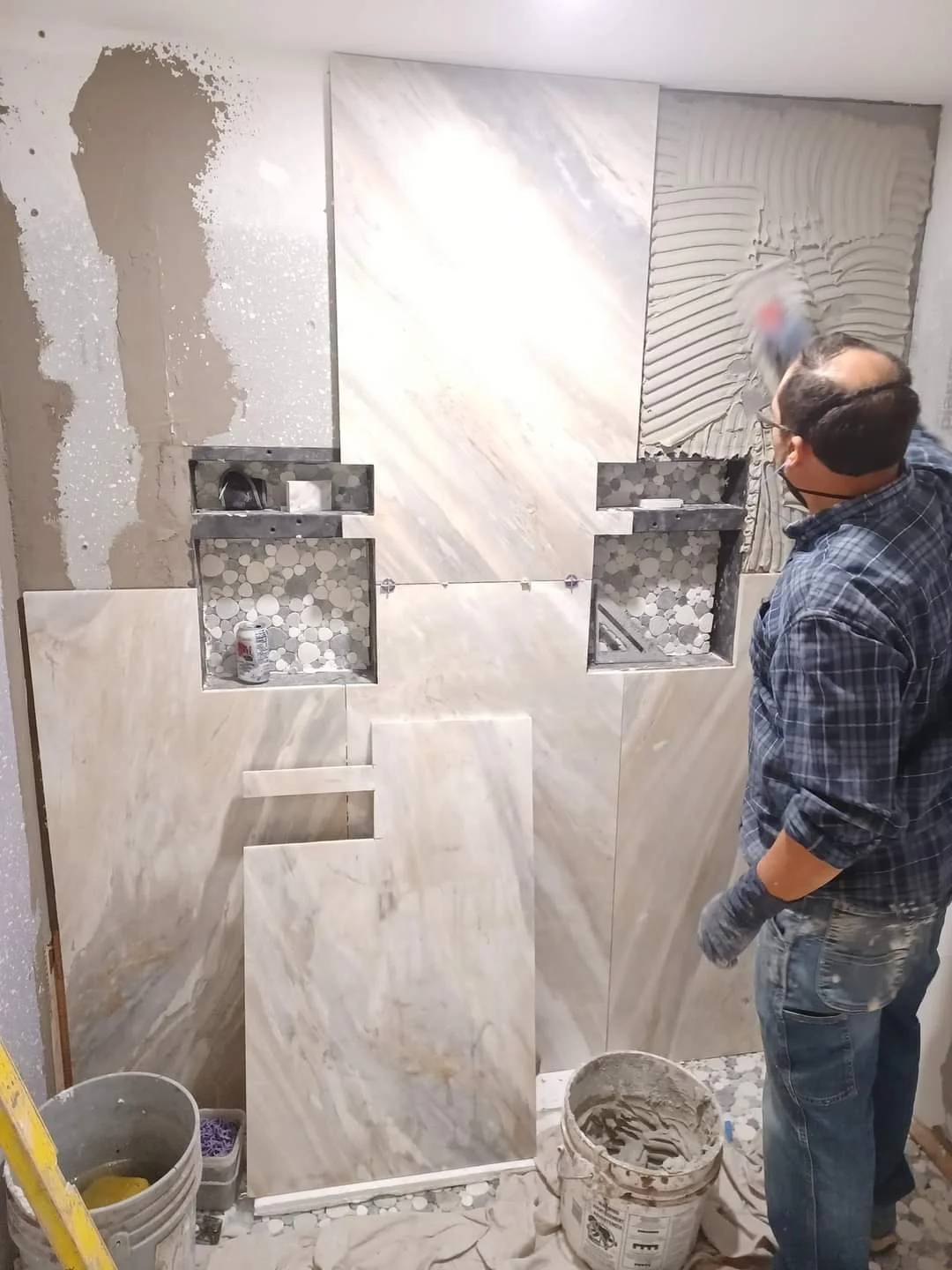 Contractor installing large format marble tile in shower with kerdi pan and mosaic niches in Westminster area of Denver suburbs.  Denshield installed and waterproofed without.  Ditra heat installed just outside shower.