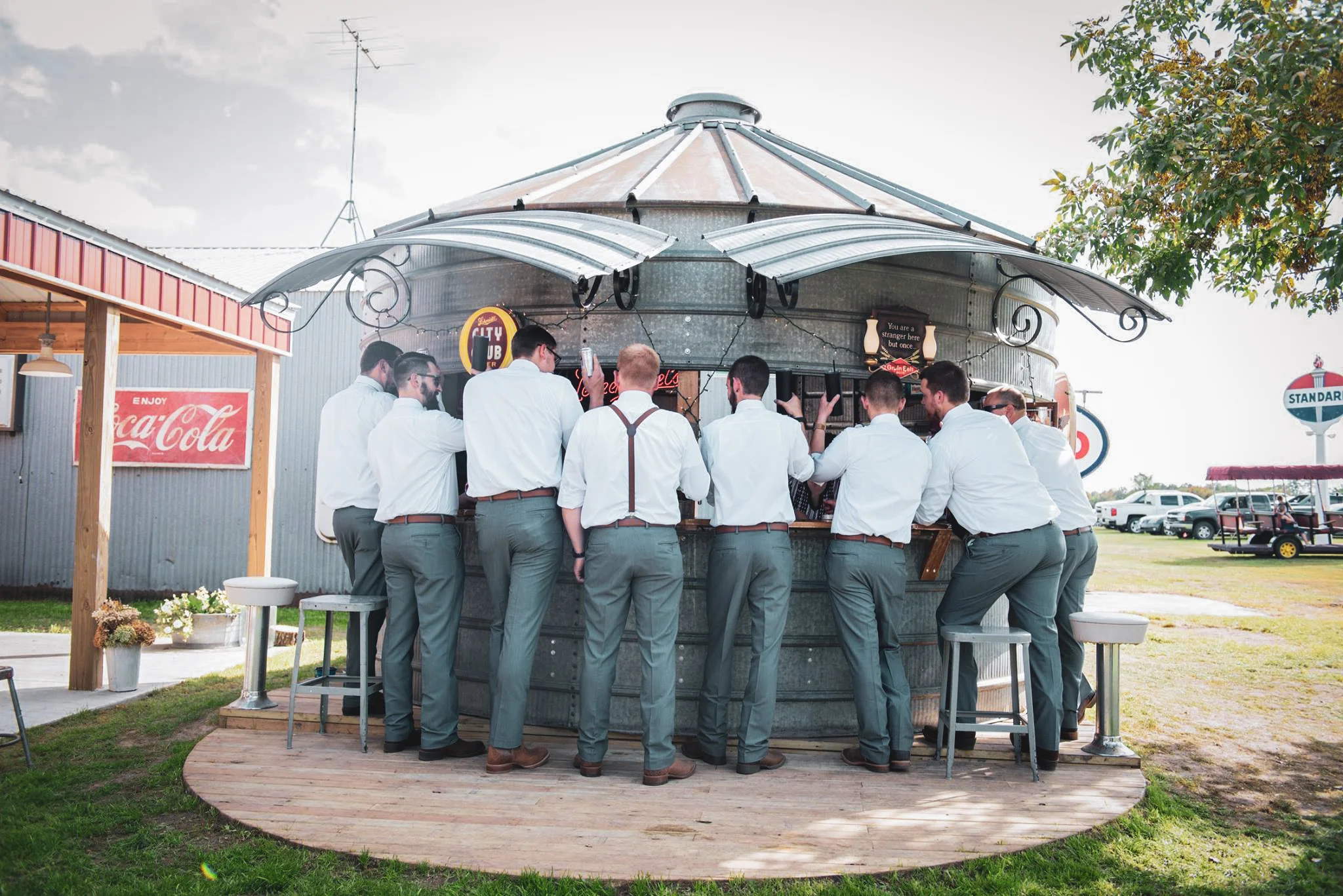 Groom and groomsmen gathered at the Grain Bin Bar at Adler Ranch wedding venue near Alexandria, Minnesota, enjoying a relaxed moment in the outdoor bar area designed for easy guest flow and socializing during the reception
