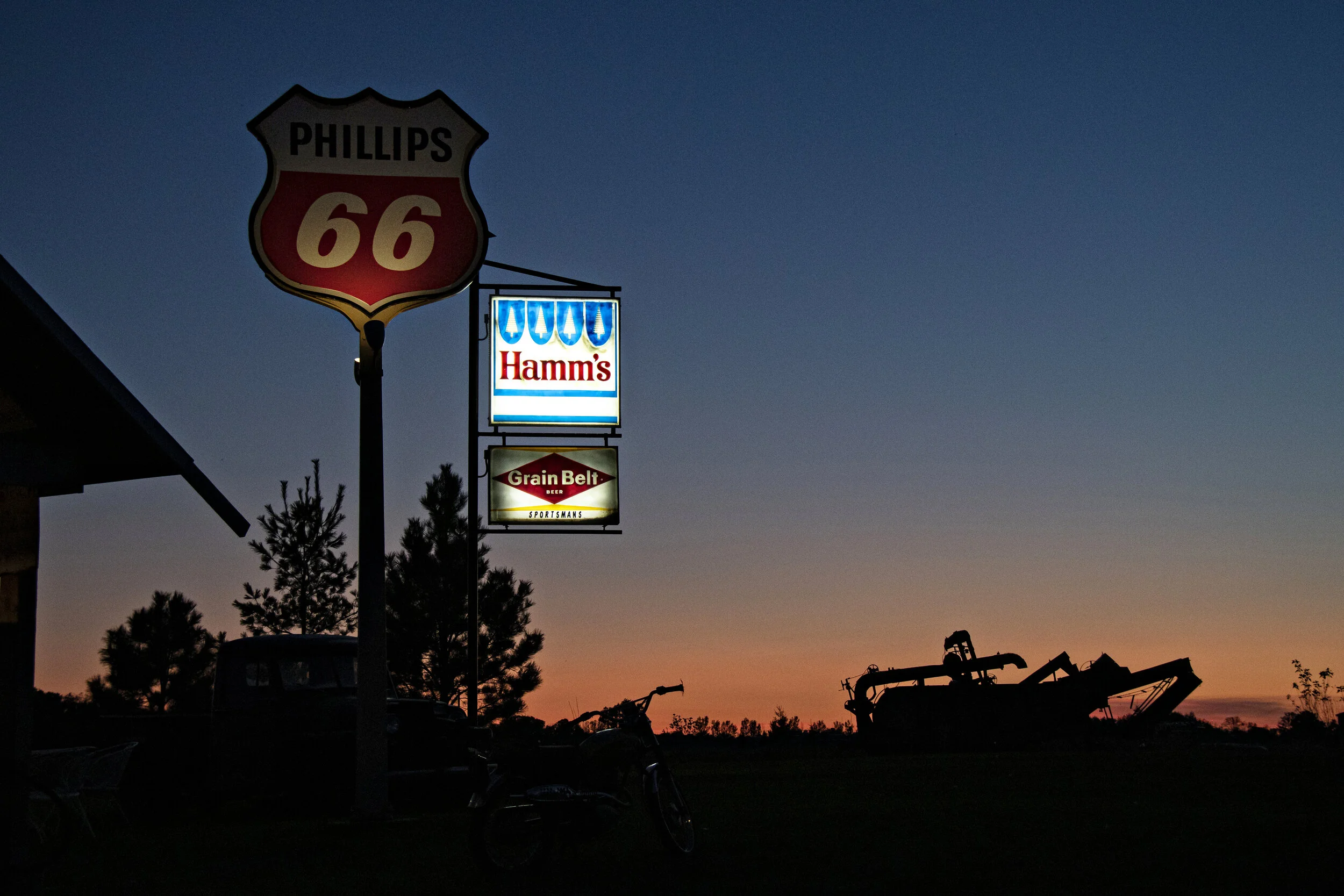 Golden hour sunset over vintage signs and antique farm equipment at Adler Ranch near Alexandria, MN.