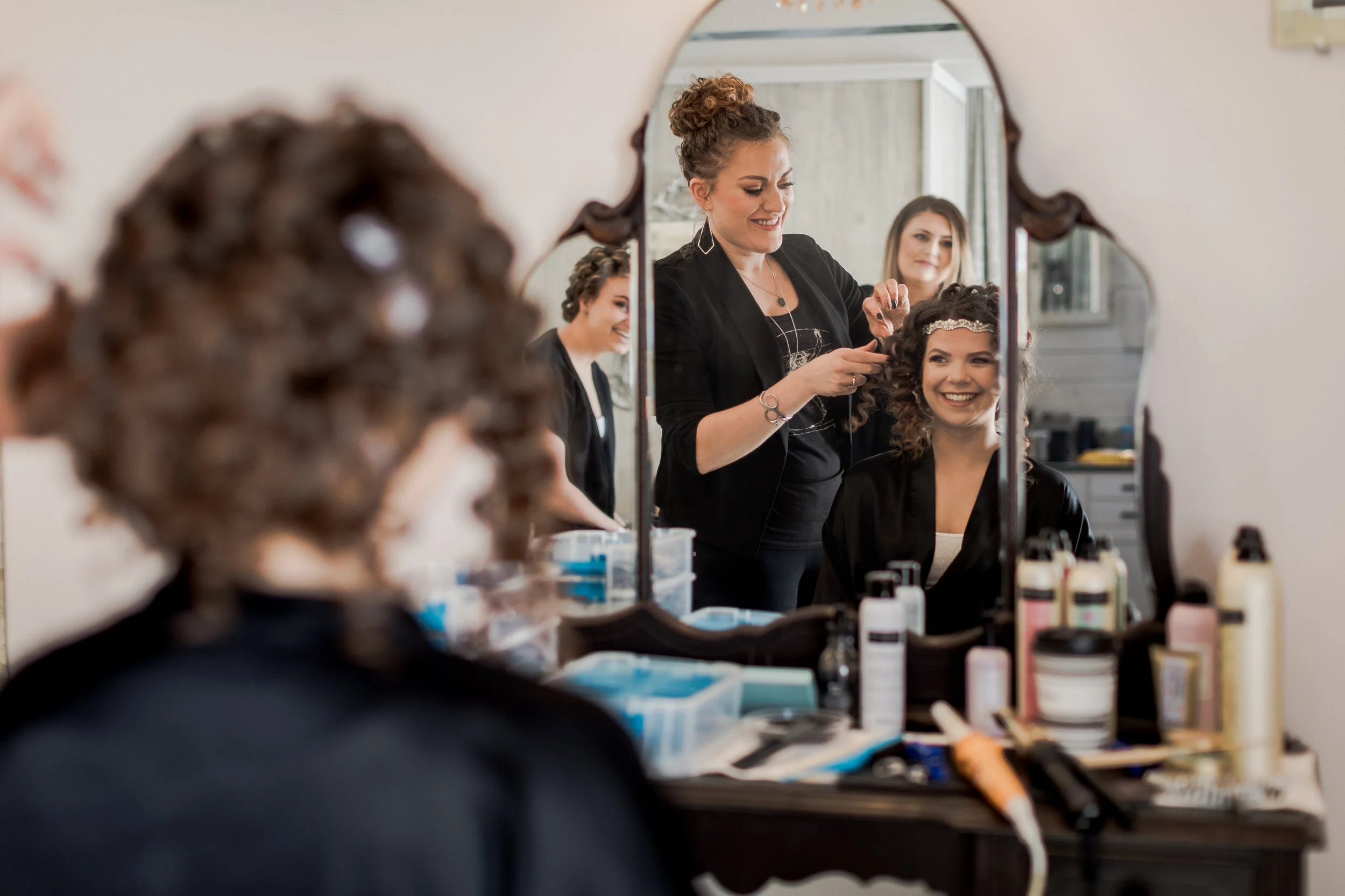 Hairdresser styling bride’s hair inside The Cabin getting-ready suite at Adler Ranch Wedding Venue in Alexandria, Minnesota.
