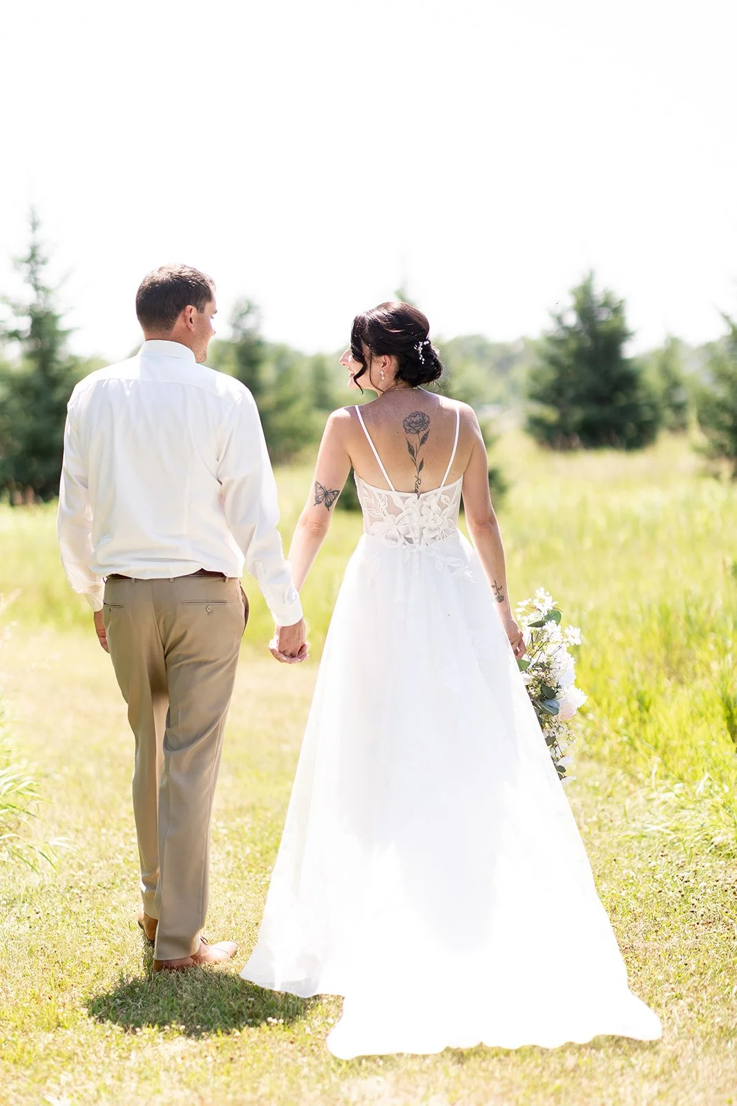 Bride &amp; Groom walking in the wildflower field