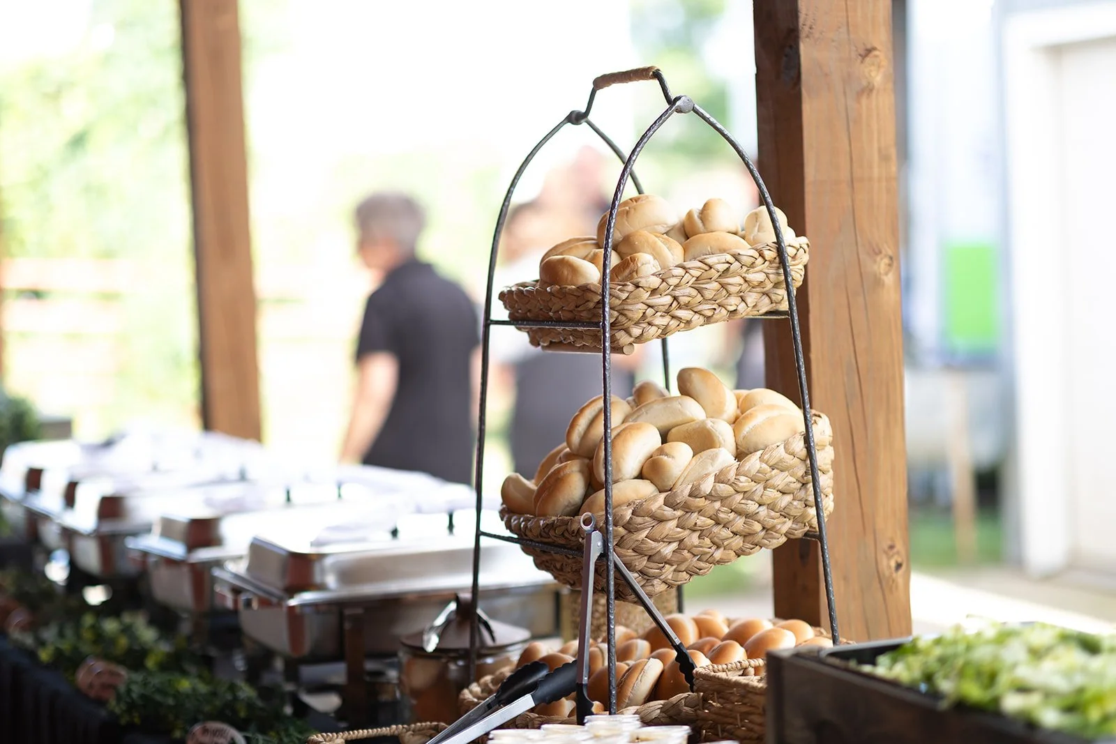 Buffet line at wedding with food service equipment and stacked breads ready for service at Adler Ranch