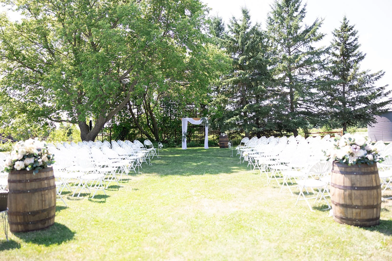 Ceremony set with white chairs, whiskey barrels with florals at Adler Ranch Wedding Venue