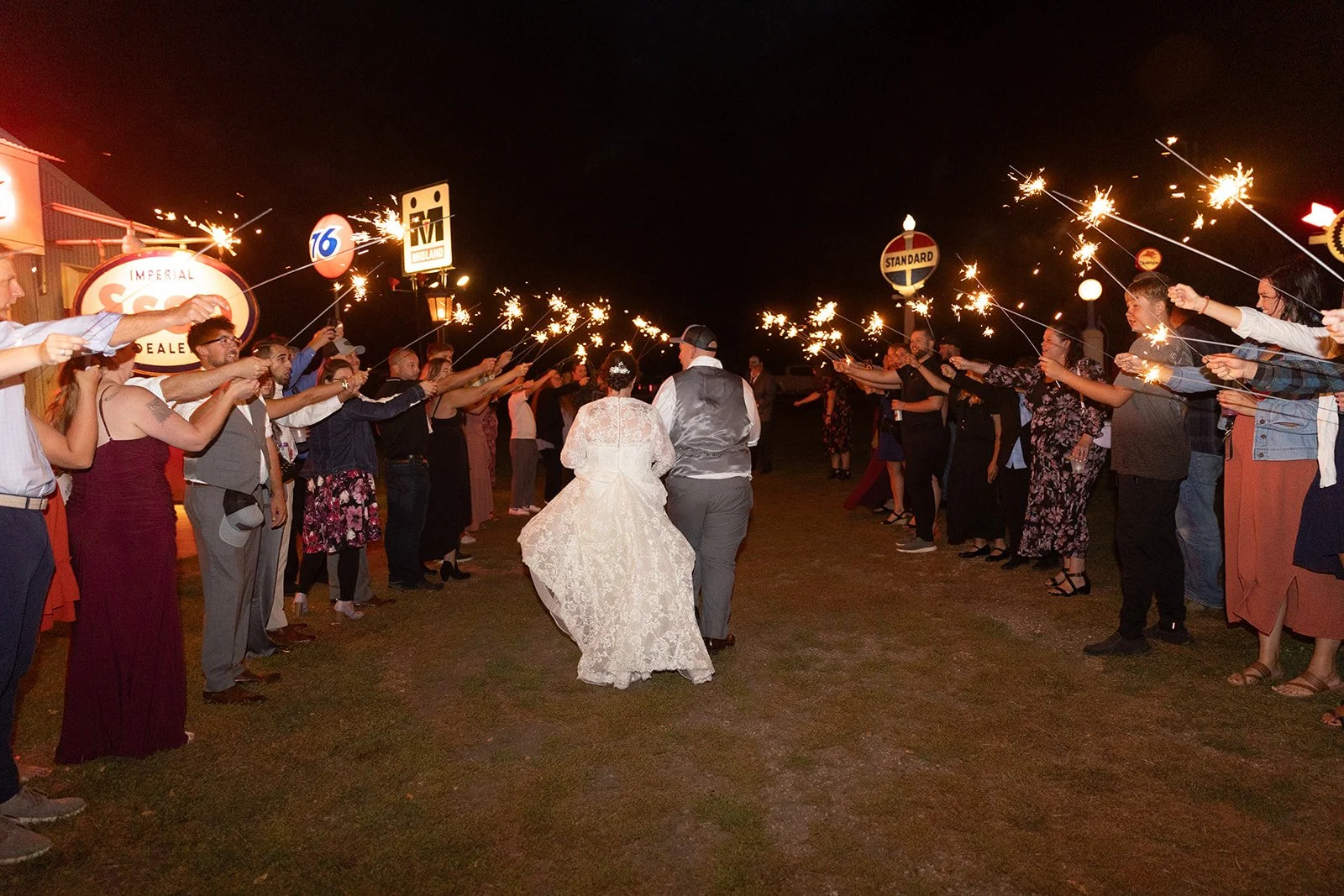 Happy couple exit the venue with a sparkler exit at Adler Ranch under the light of the vintage lighted signs