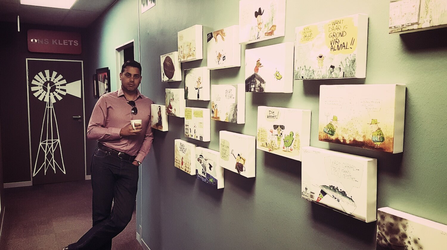 Jerm alongside a wall of his work at Maroela Media.