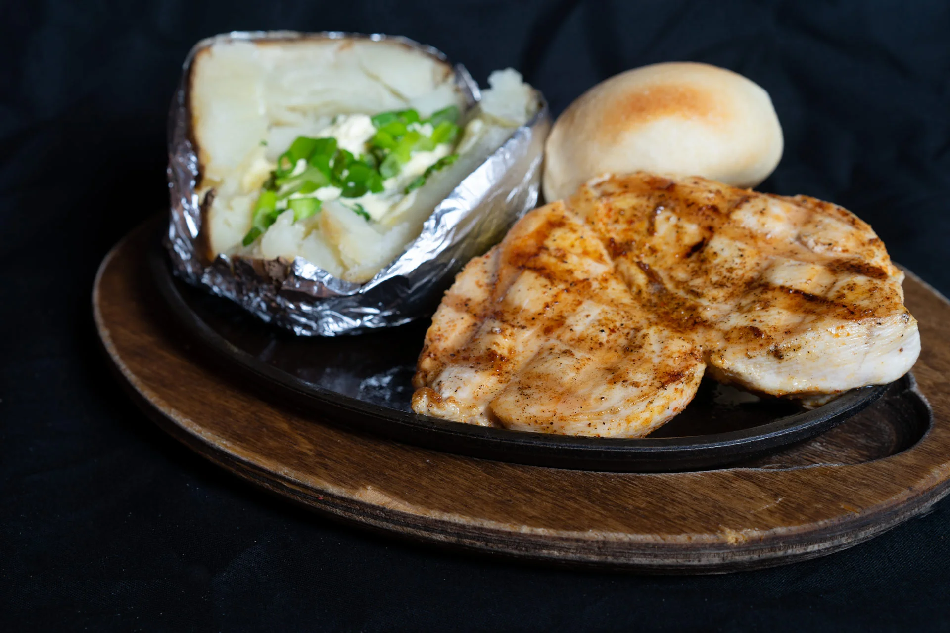 Grilled Chicken Breast 8 oz. boneless chicken breast lightly seasoned, grilled and served with a baked potato and in-house prepared yeast roll. 11.00