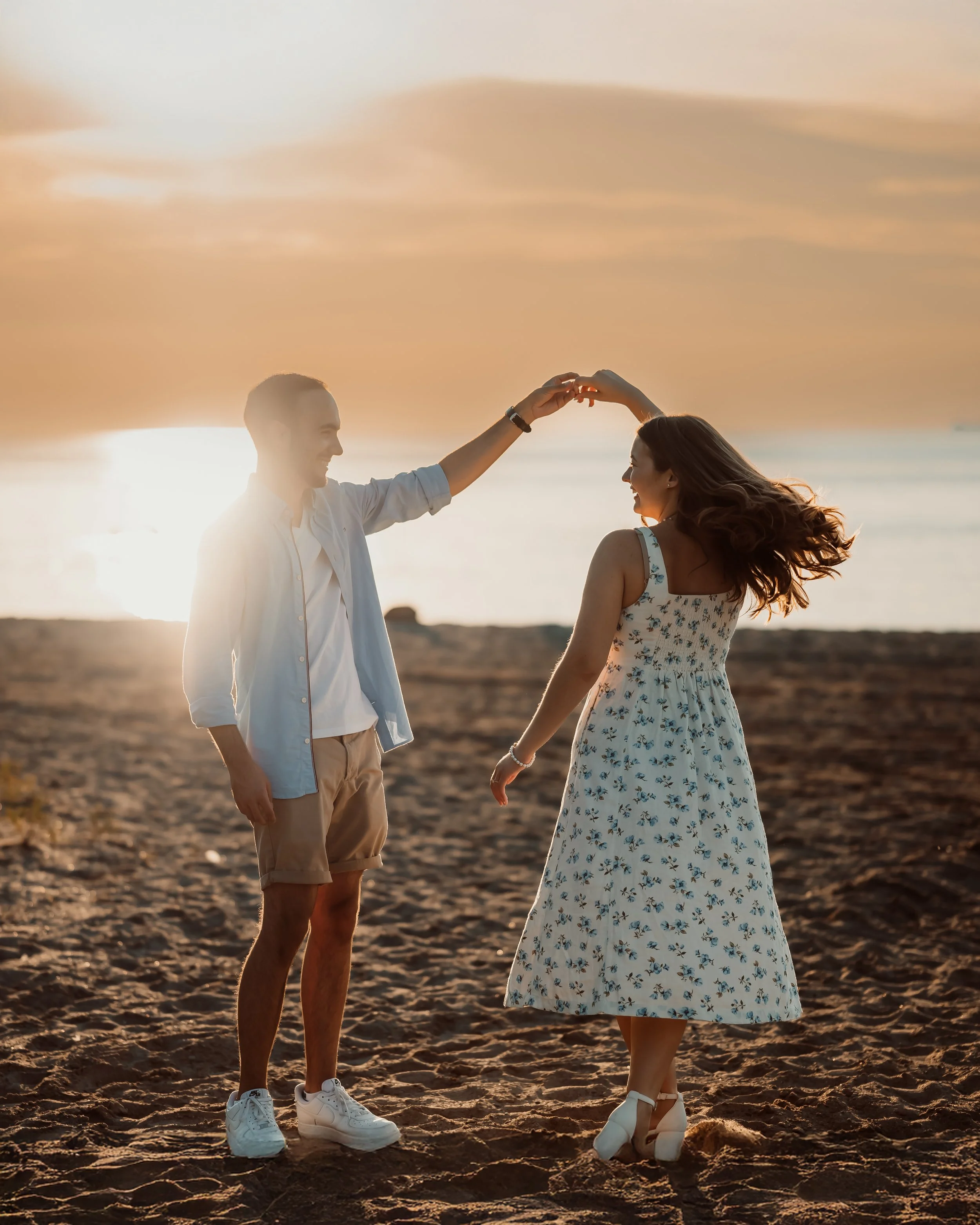 St. Catharines engagement photographer captures couple twirling on Sunset Beach at sunset