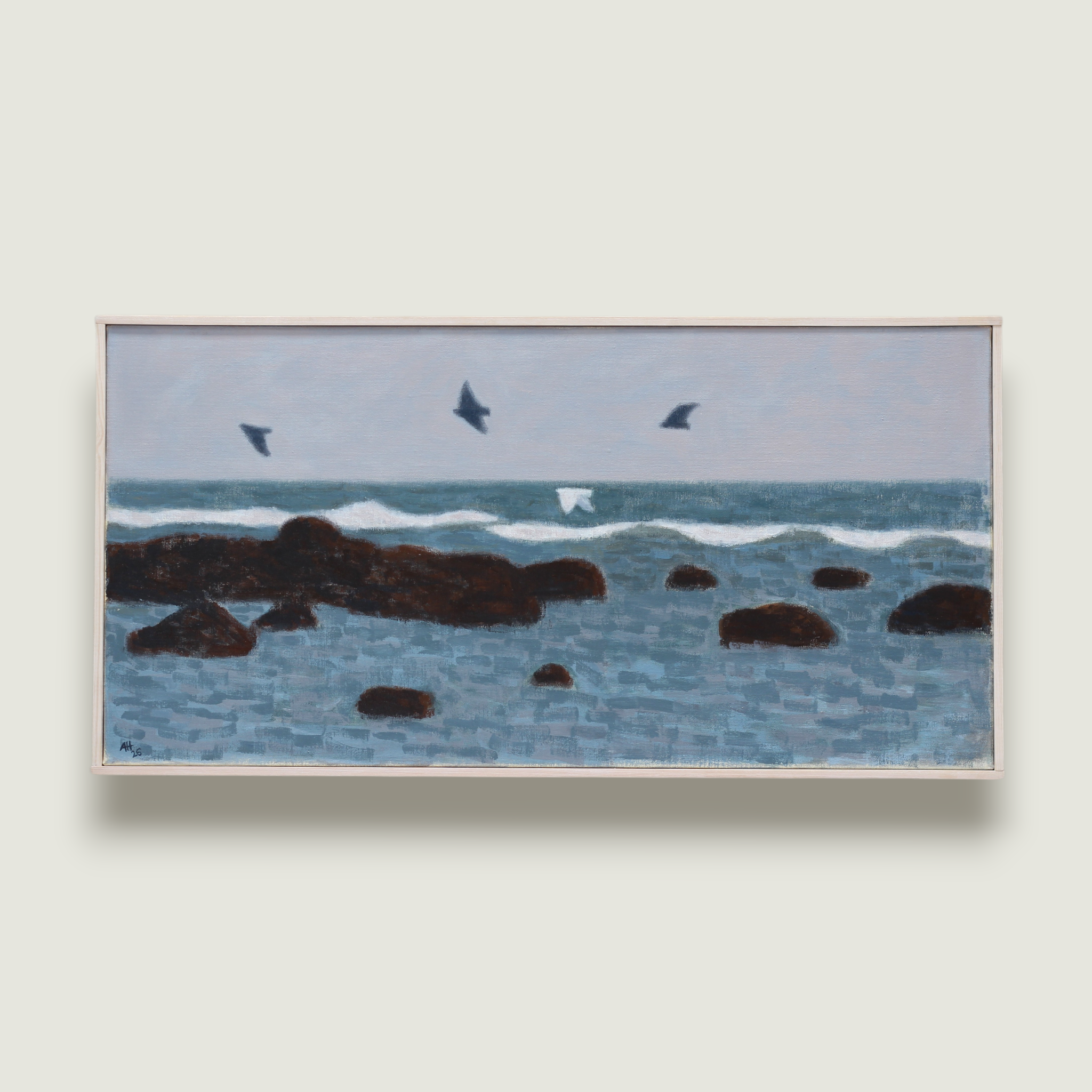Four gulls flying over rocks