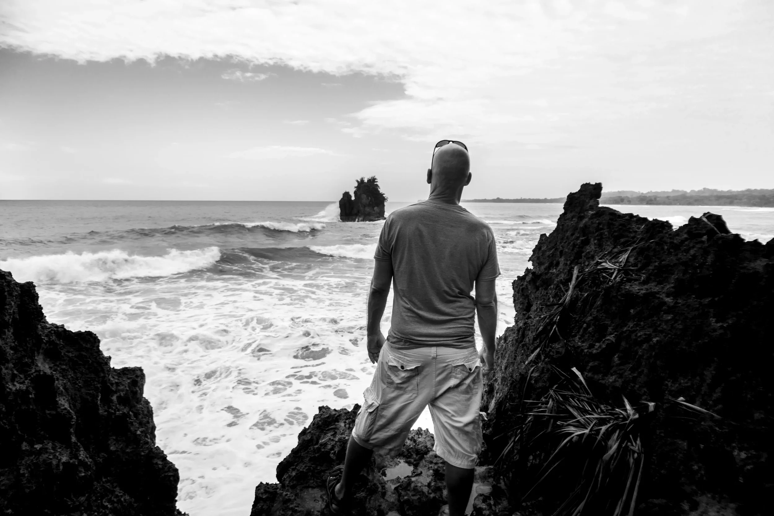 Author Phil Williams looks out at crashing waves from the rocks at Playa Cocles, Puerto Viejo, Costa Rica