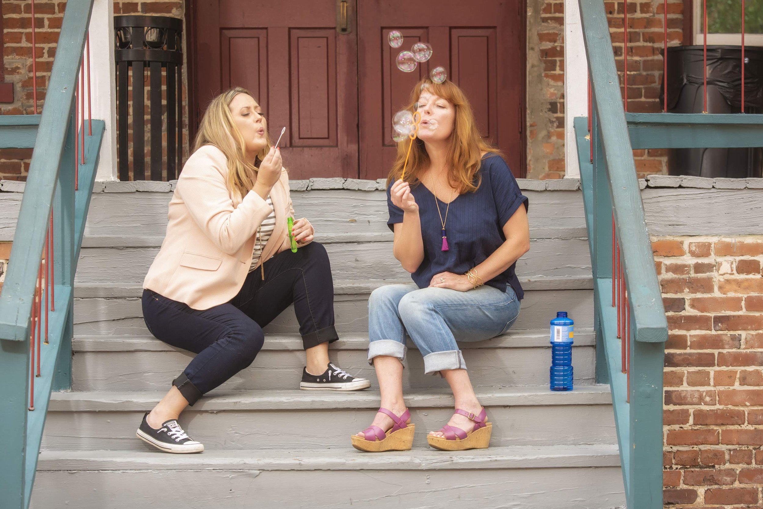 Teresa and Kelly playfully blowing bubbles on the steps of an old building