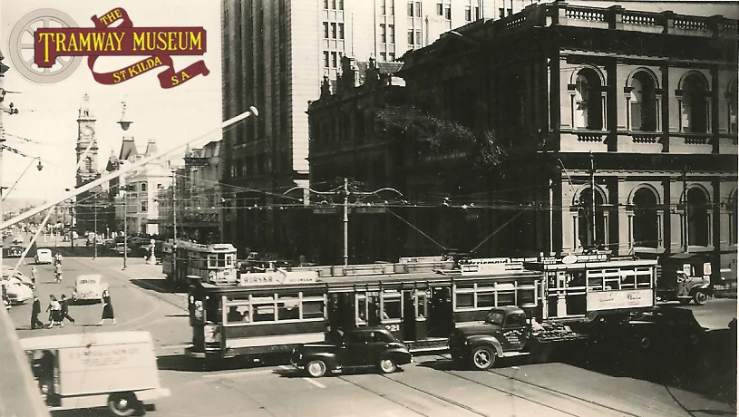 A busy 1954 scene at the intersection of King William Street/Grenfell Street/Currie Street. Two 'Drop Centre' trams are crossing over King William Street bound for both the eastern and western suburbs while a third 'Drop Centre' waits for its' turn to cross the intersection bound for one of the northern suburbs. Trams would eventually return to this part of King William Street in 2007.