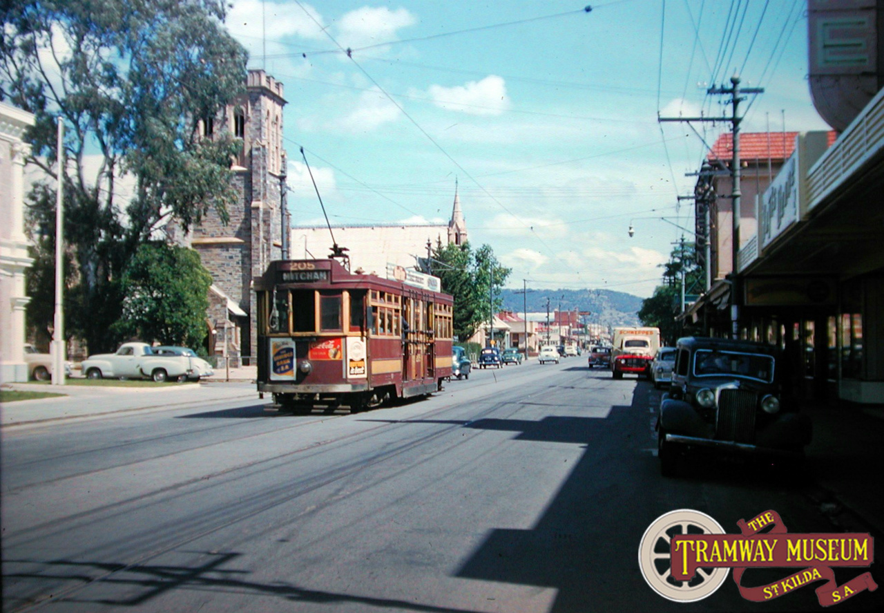 'Drop Centre' tram 205 is seen here in Unley Road heading towards Mitcham in the mid 1950s. Some elements of this scene have remained the same since the trams ceased running on Unley Road with the two churches on the left of the road still standing. The present day Coles Supermarket would be where the local shops are on the right of this shot. Photo: Keith Kings.