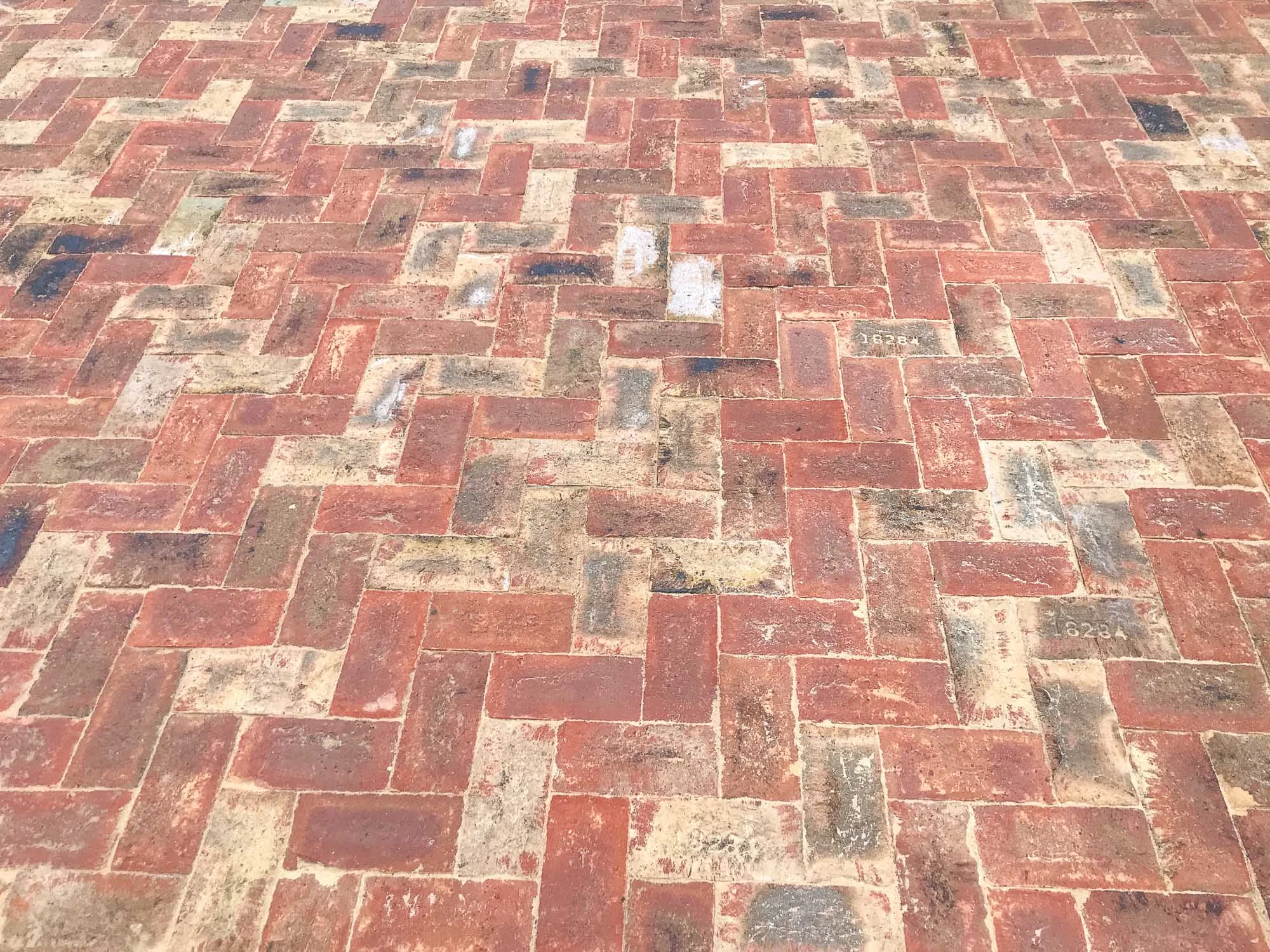 The mix of red, buff and black/blue colours in this brick patio creates a mottled pattern which is a far cry from the rather stark appearance of modern paving setts